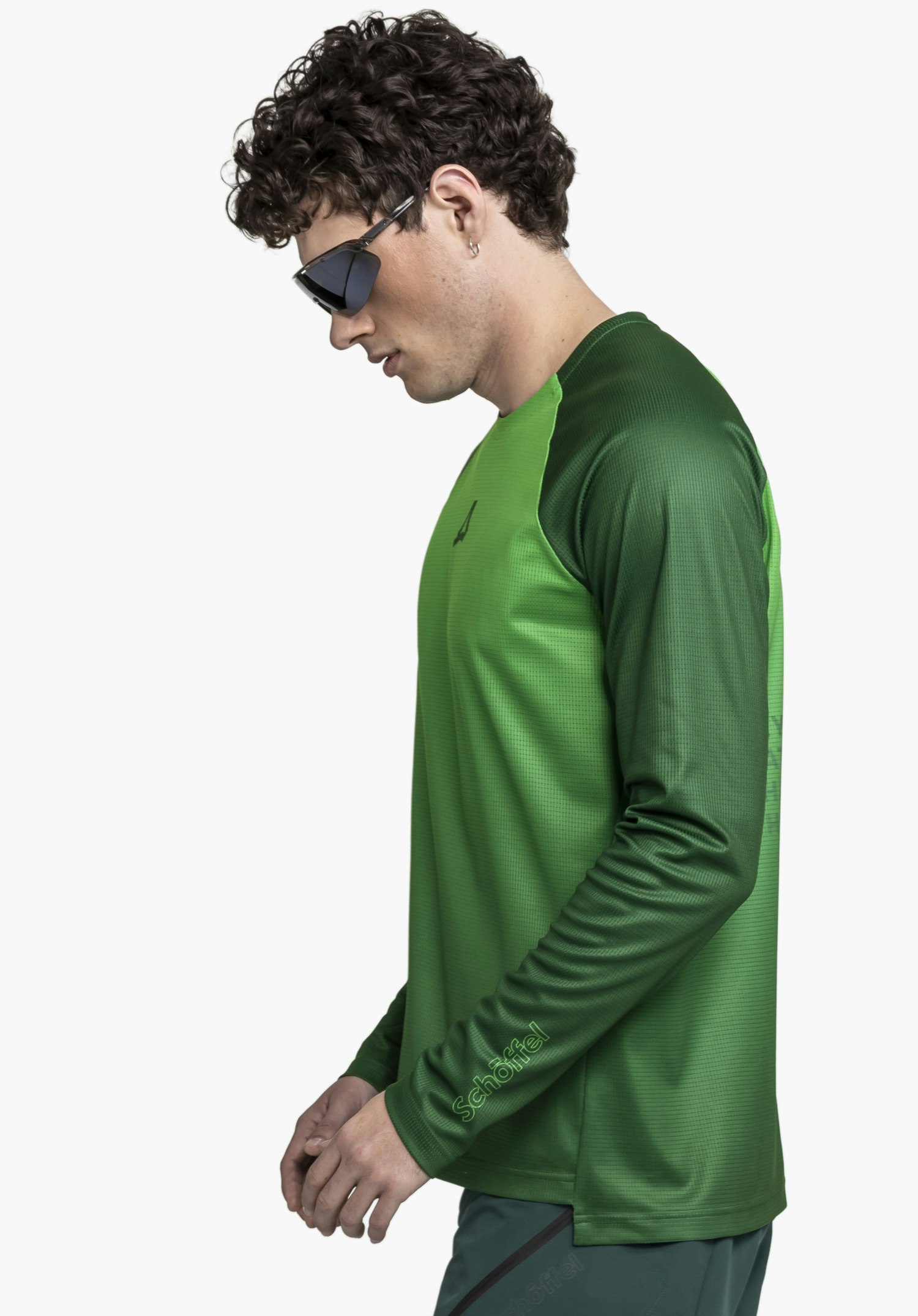 Longsleeve Style Koitere MEN in green: A model wearing sunglasses is captured in profile against a neutral background, showcasing the long-sleeved shirt with the Schöffel logo subtly visible on the cuff.