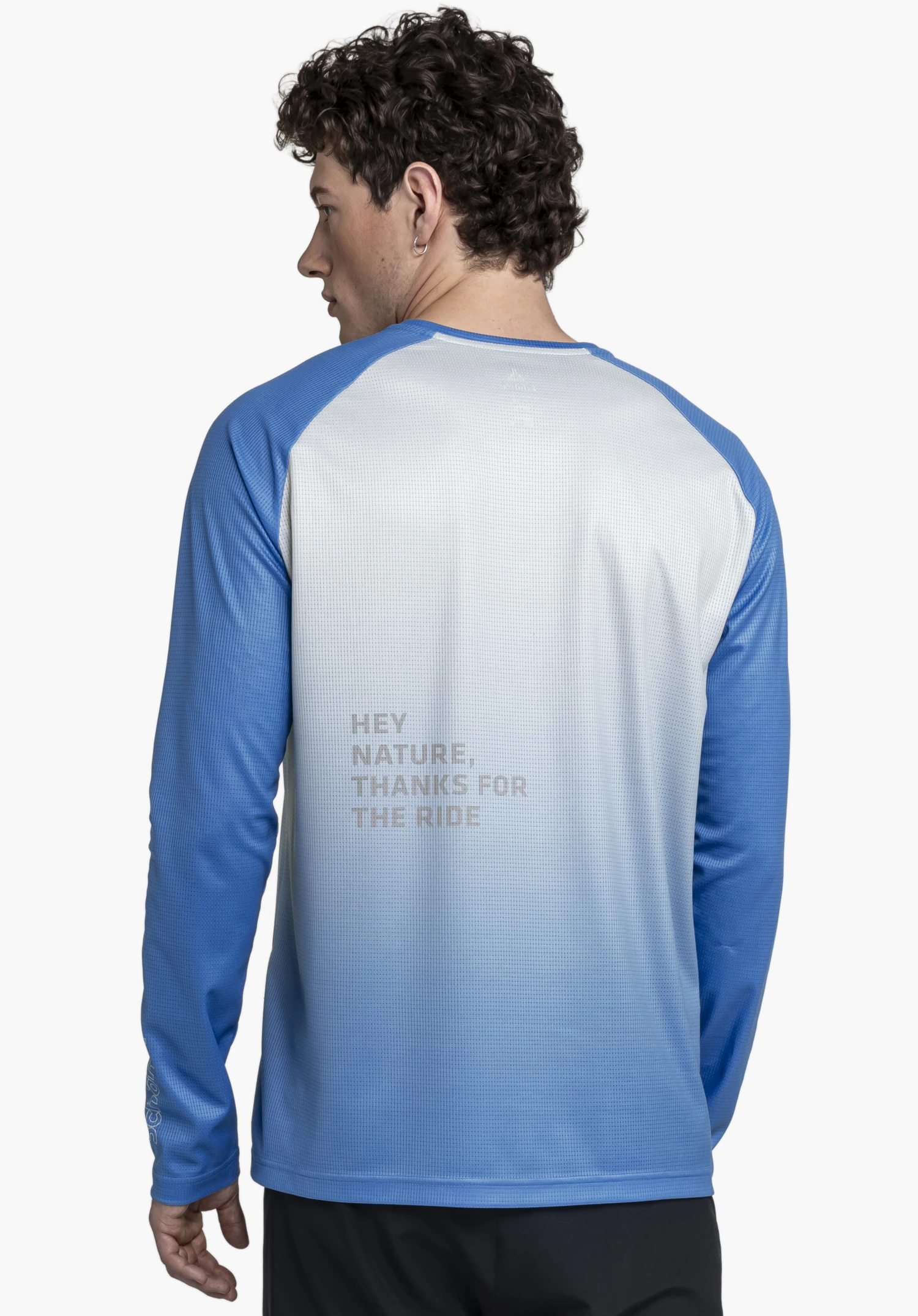 Longsleeve Style Koitere MEN en bleu : Le mannequin présente une vue de dos devant un fond neutre. Les manches et les épaules contrastées en bleu sont complétées par un dos clair agrémenté d'une inscription discrète. Le logo Schöffel sur la manche complète ce look sportif.