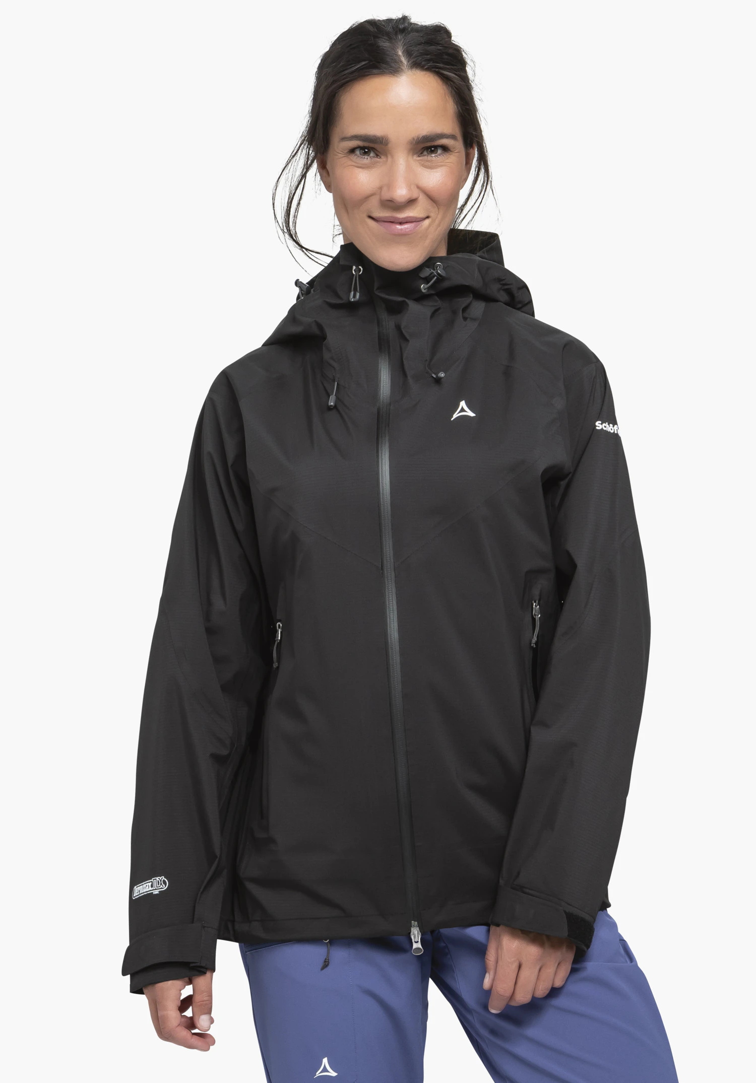 Jacket Style Blaueis WMS veste de pluie noire avec logo Schöffel, portée de face par une personne souriante aux mains détendues; pantalon bleu foncé, fond clair. Texte:Schöffel.