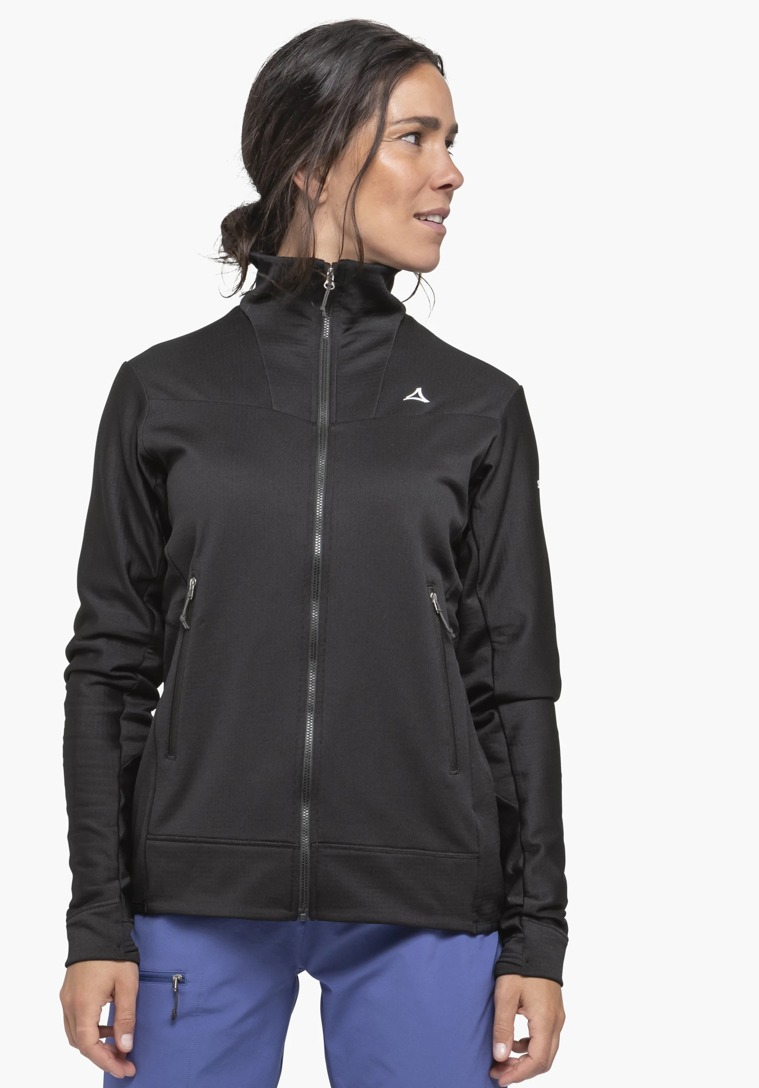 Fleece Jkt Style Blaueis WMS an einem Model in der Farbe Schwarz. Die Frau steht frontal, blickt zur Seite und trägt die geschlossene Jacke mit durchgehendem Frontreißverschluss und dem Schöffel-Logo auf der linken Brust vor einem neutralen Hintergrund.