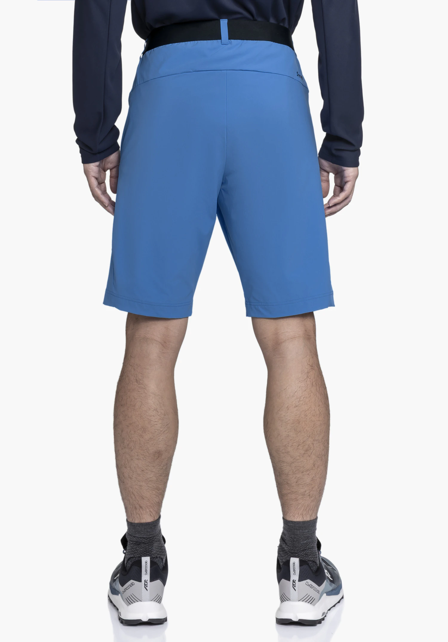 Shorts Style Blaustein MNS in blue, worn by a model in back view. The shorts feature a black waistband and the Schöffel logo is visible on the right side. The model stands against a neutral background.