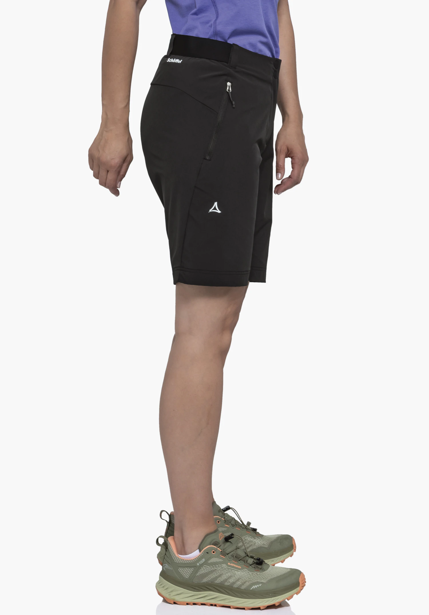 Shorts Style Blaustein WMS sur un mannequin qui se tient de profil. On y voit le short de couleur noire avec un logo Schöffel bien visible sur le côté de la jambe, photographié sur un fond neutre.