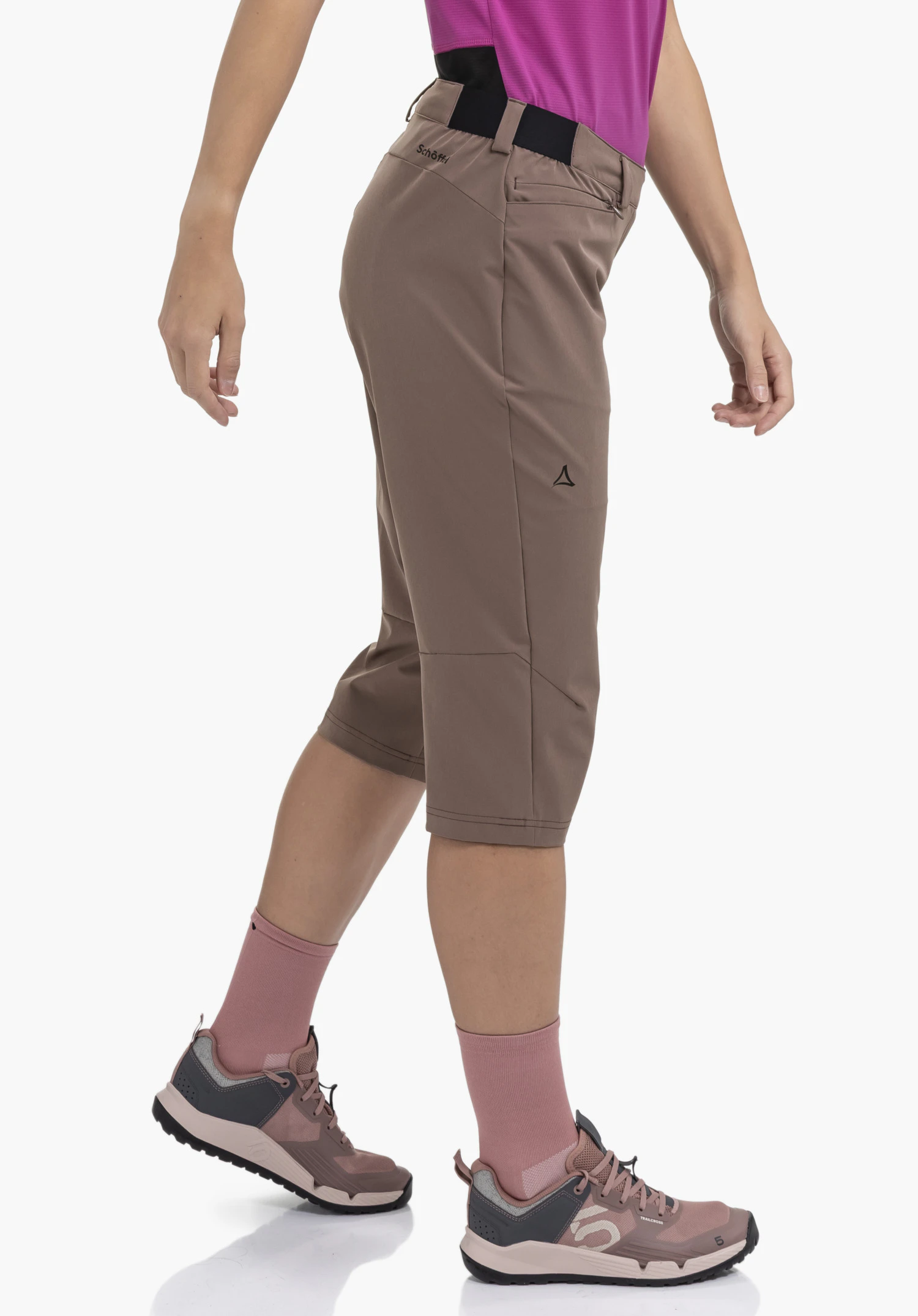 Capri Pants Style Keitele WMS in brown seen on a model in a dynamic side profile against a neutral background. The trousers feature a functional design with the subtle Schöffel logo on the waistband and below the hip, highlighting the sporty look.