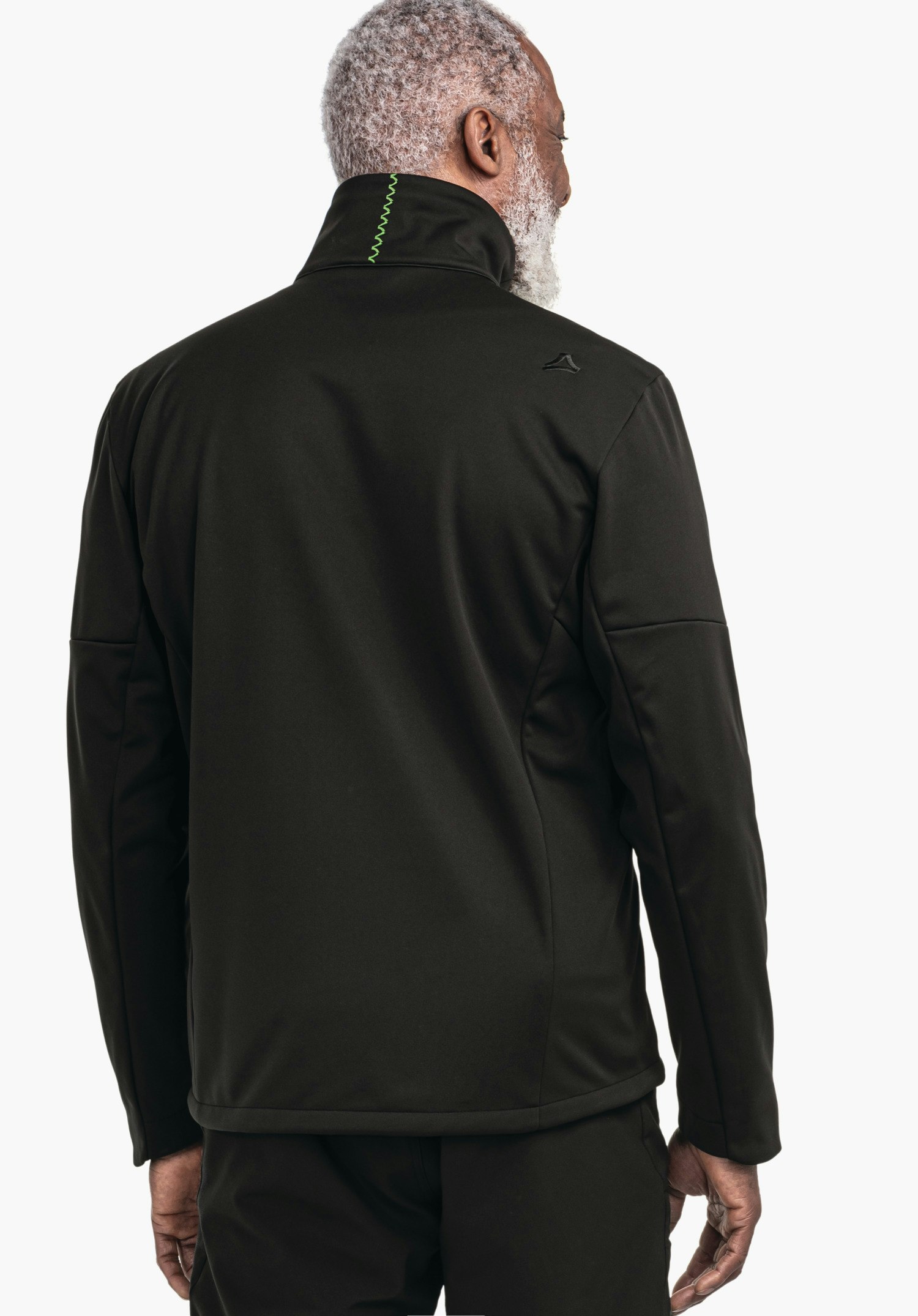 Softshell Jk Style Fracon MNS Schwarze Jacke, getragen von einem Mann, steht mit dem Rücken zur Kamera; Schöffel-Logo auf rechter Schulter, grüner Zierstich am Kragen; weißer Hintergrund.