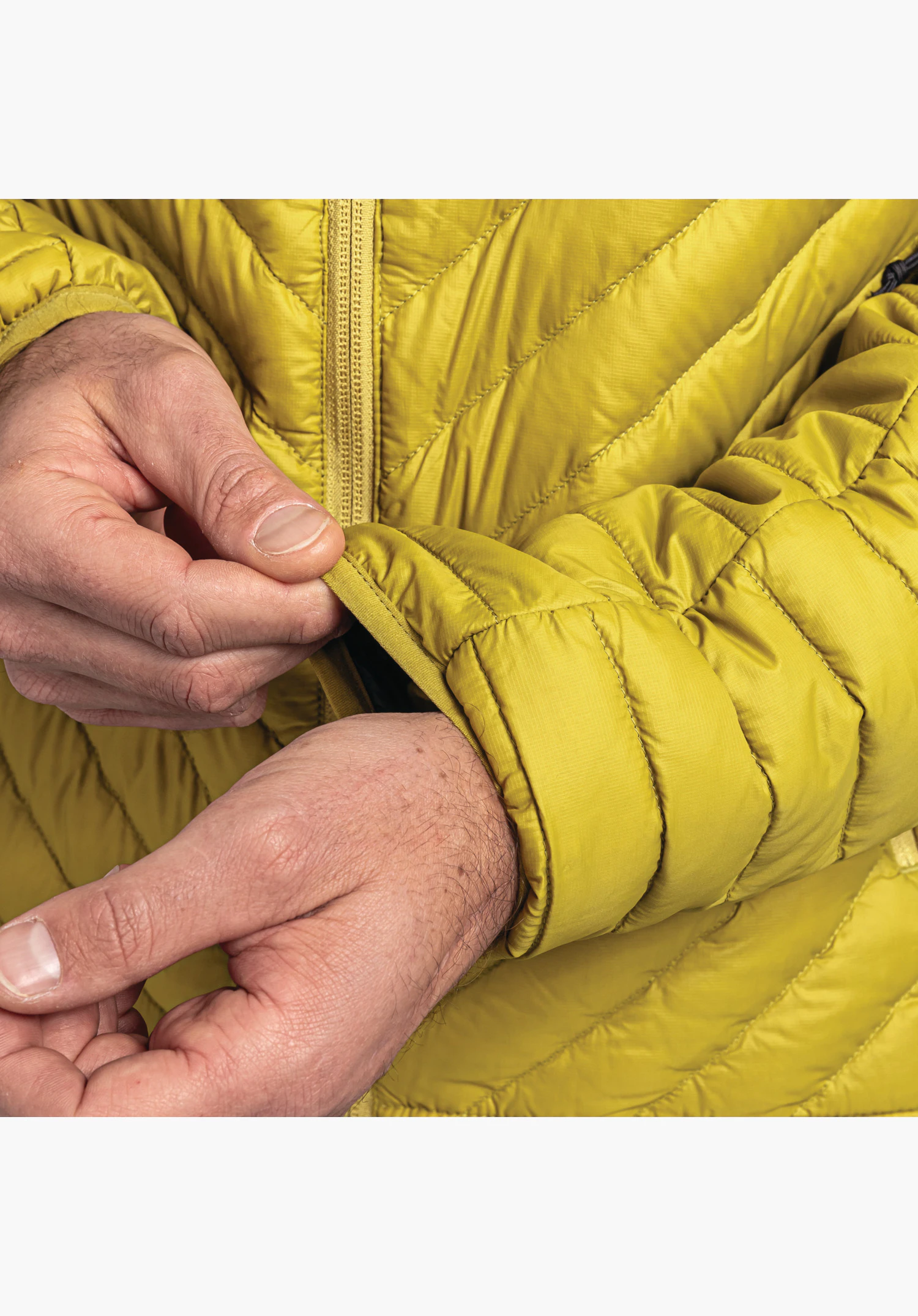 Down Jacket Style Cascata MNS. Vue détaillée du poignet élastiqué en jaune et du fin matelassage sur la manche. Gros plan sur fond blanc/neutre.