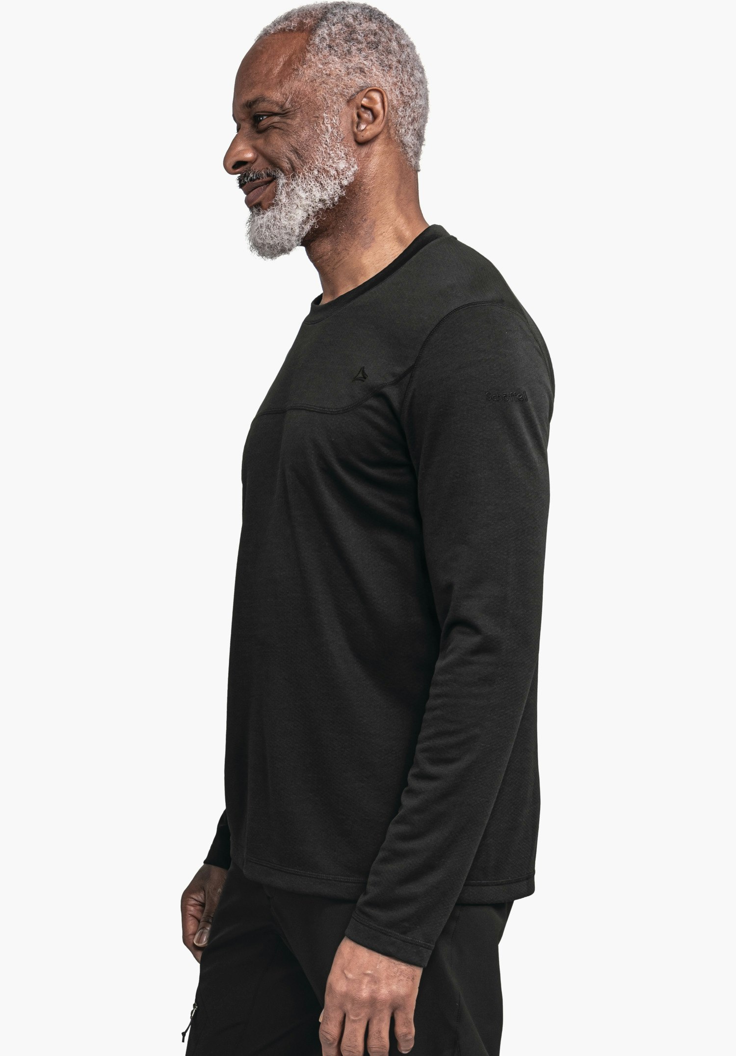 CIRC Longsleeve Style Smue MNS dunkel schwarzes, langärmeliges Shirt mit kleiner Schöffel-Logo auf der Brust, seitlich getragen von einem älteren Mann, lächelnd, vor neutralem weißem Hintergrund.