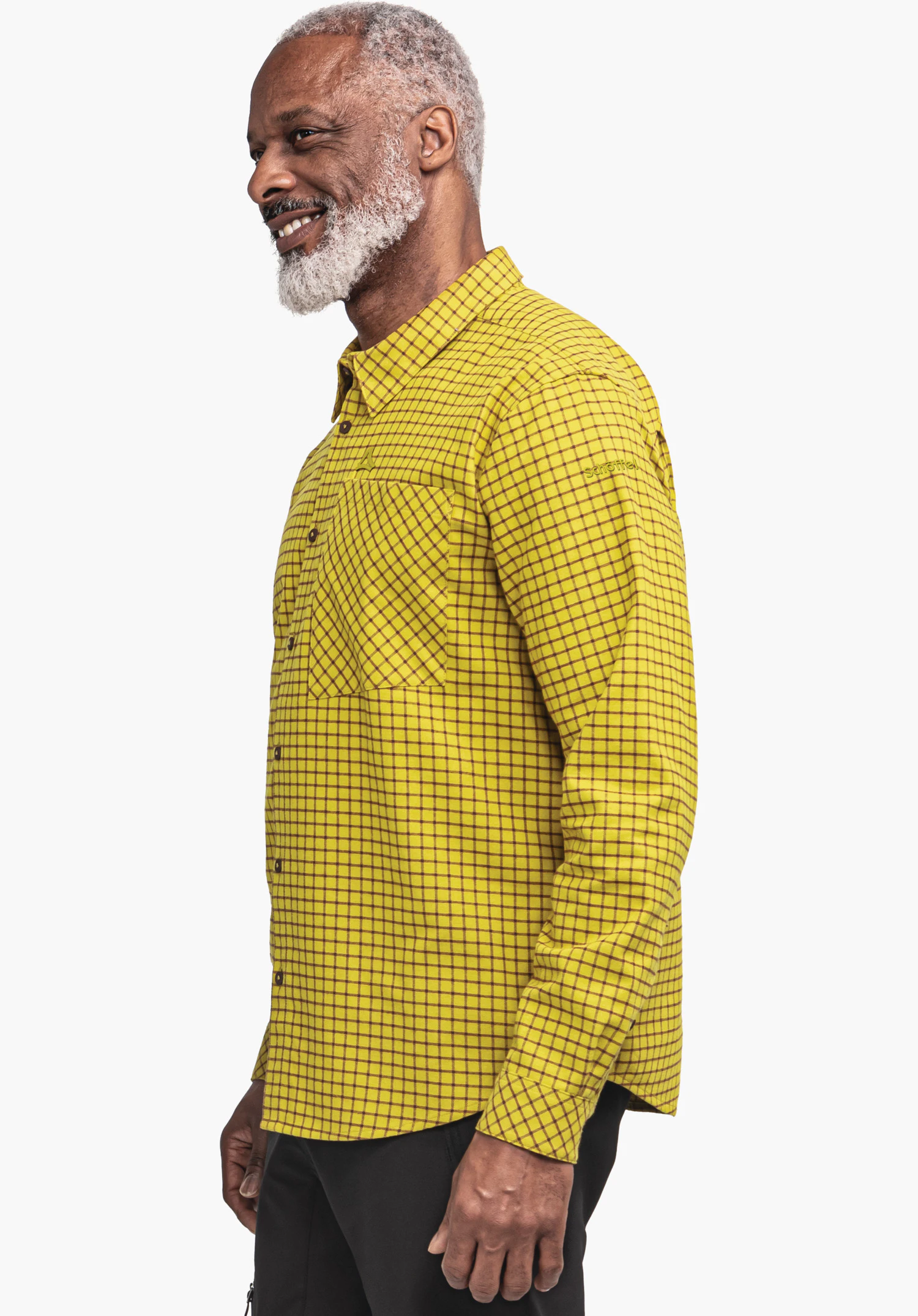 Shirt Style Boyoma MNS Mann trägt hellgelbes Hemd mit schwarzem Karomuster, steht seitlich und lächelt, sichtbarer weißer Bart und Haare, trägt schwarze Hose; neutraler weißer Hintergrund.