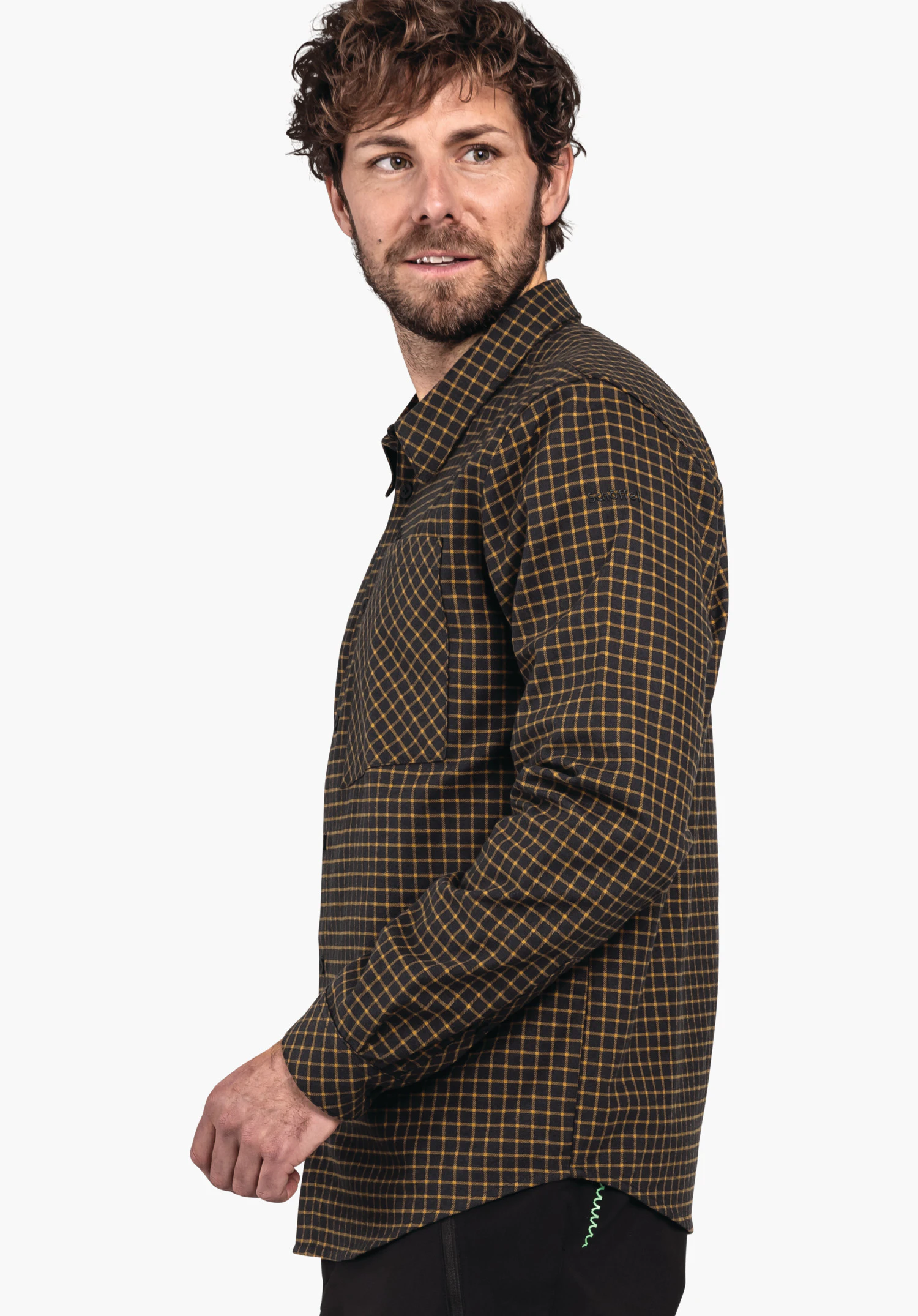 Shirt Style Boyoma MNS dunkel schwarzes Hemd mit gelbem Karomuster; Mann trägt es und blickt über die Schulter; neutraler weißer Hintergrund, sichtbare Hand am Körper und schwarze Hose.