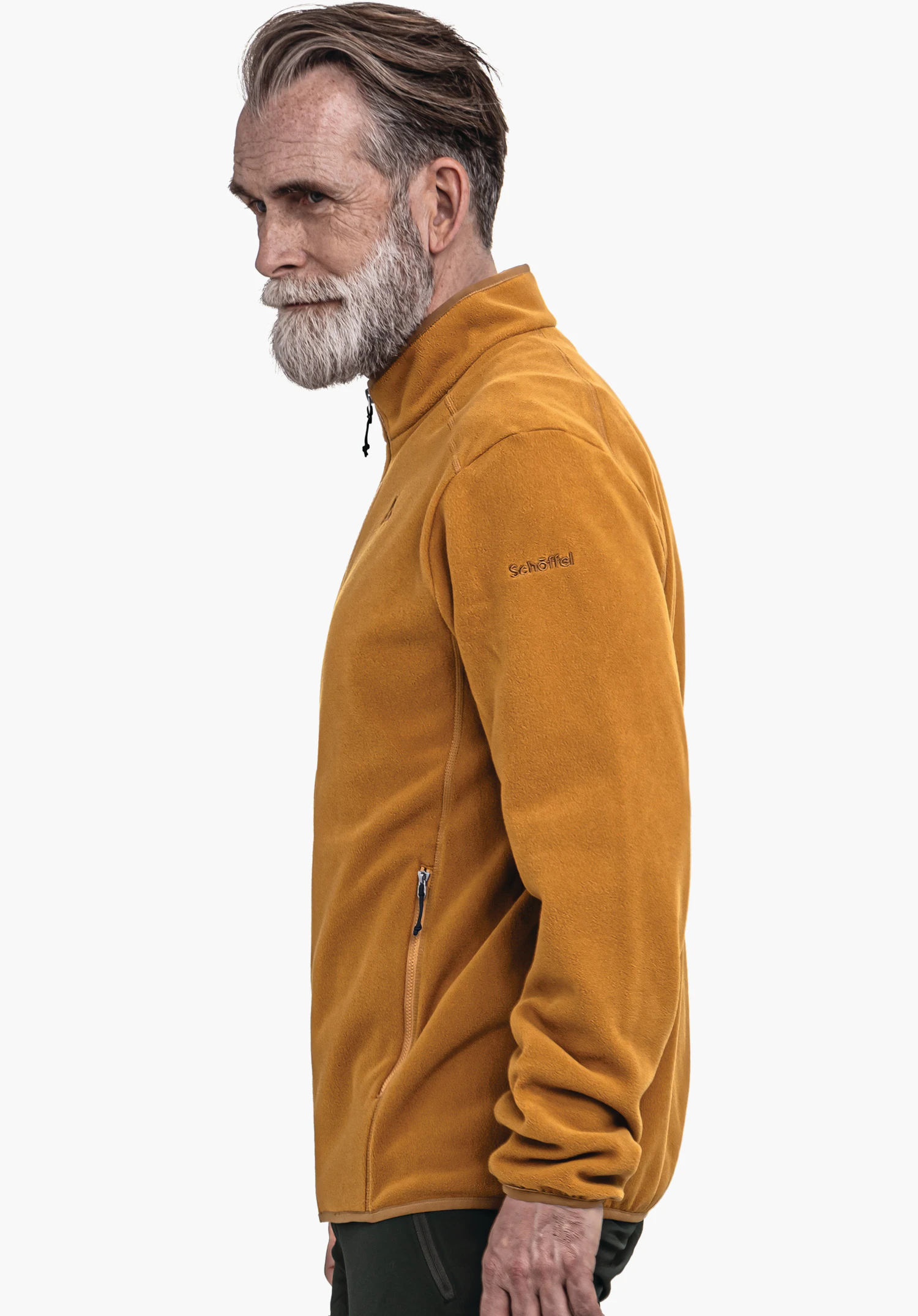 Fleece Jk Style Ash MNS dark yellow fleece jacket worn by an older man standing side-on and looking forward; neutral white background. Text on sleeve: "Schöffel"., Fleece Jk Style Ash MNS dark yellow fleece jacket worn by an older man standing side-on and looking forward; neutral white background. Text on sleeve: "Schöffel".