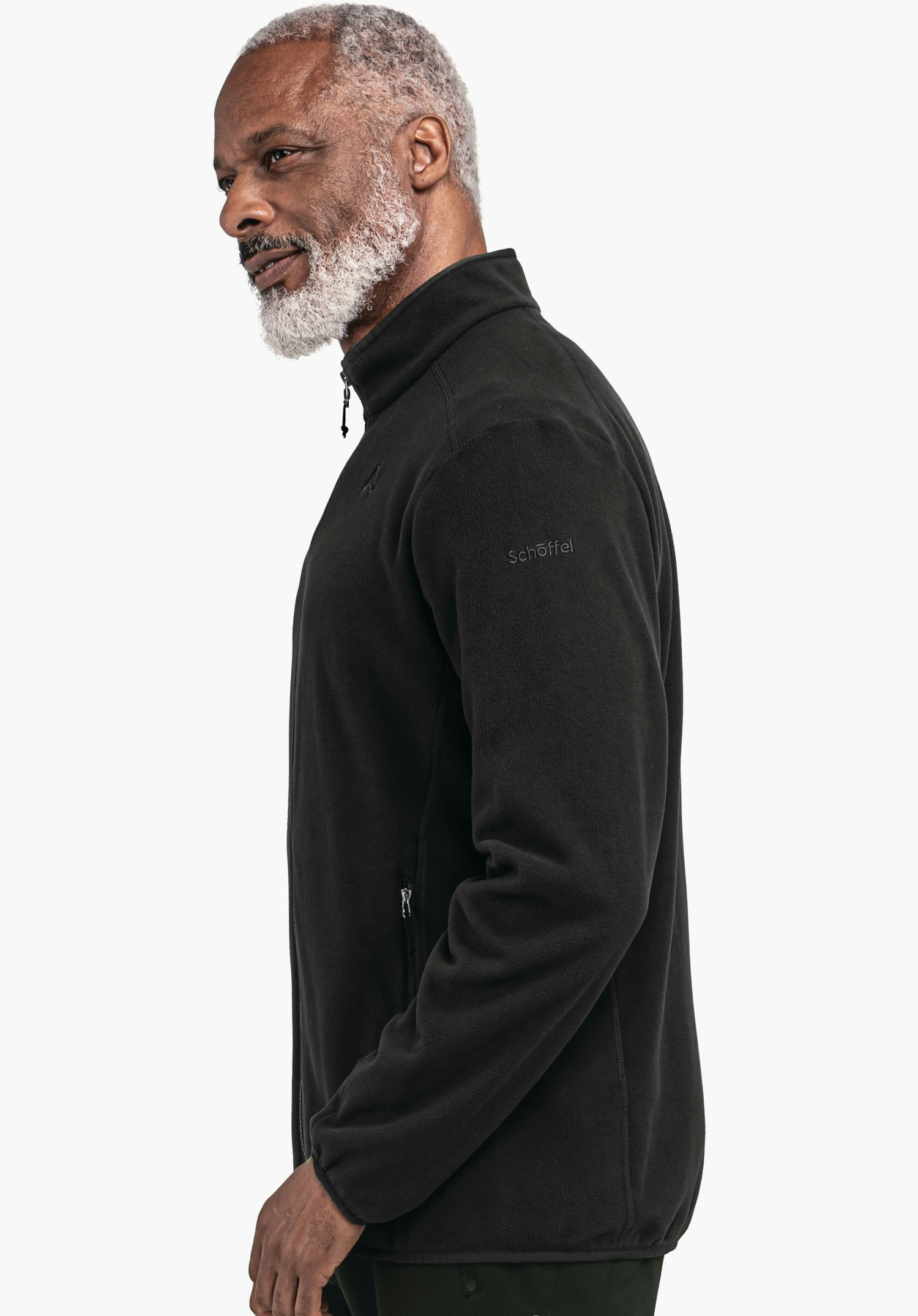 Fleece Jk Style Ash MNS schwarze Fleecejacke mit Reißverschluss, Schöffel-Logo und Text "Schöffel", getragen von älterem Mann mit weißem Bart, blickt seitlich vor weißem Hintergrund.