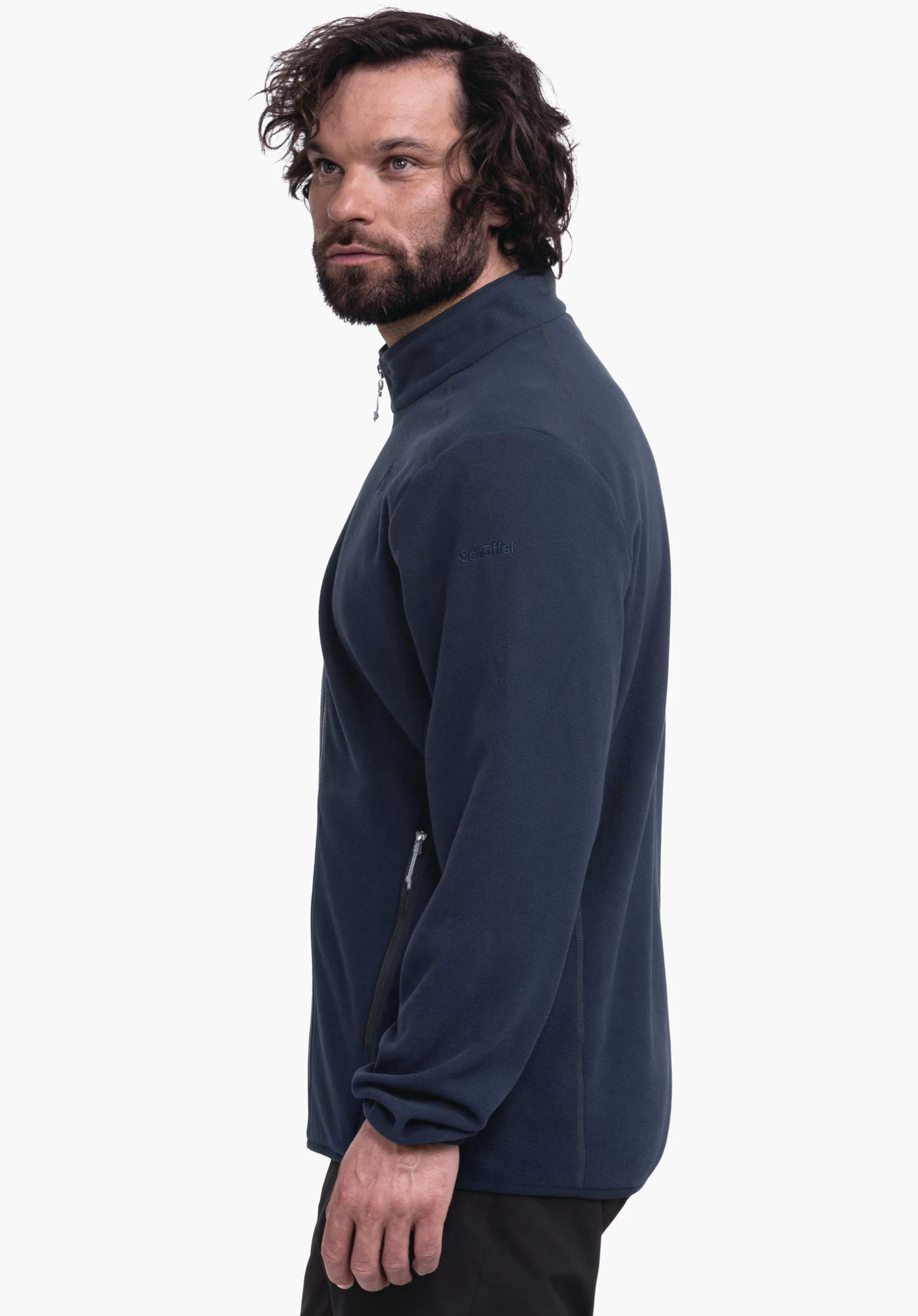 Fleece Jk Style Ash MNS dark blue fleece jacket worn by a bearded man standing side-on and looking upwards to the right; side zip pockets visible; white background. Text: "Schöffel"., Fleece Jk Style Ash MNS dark blue fleece jacket worn by a bearded man standing side-on and looking upwards to the right; side zip pockets visible; white background. Text: "Schöffel".