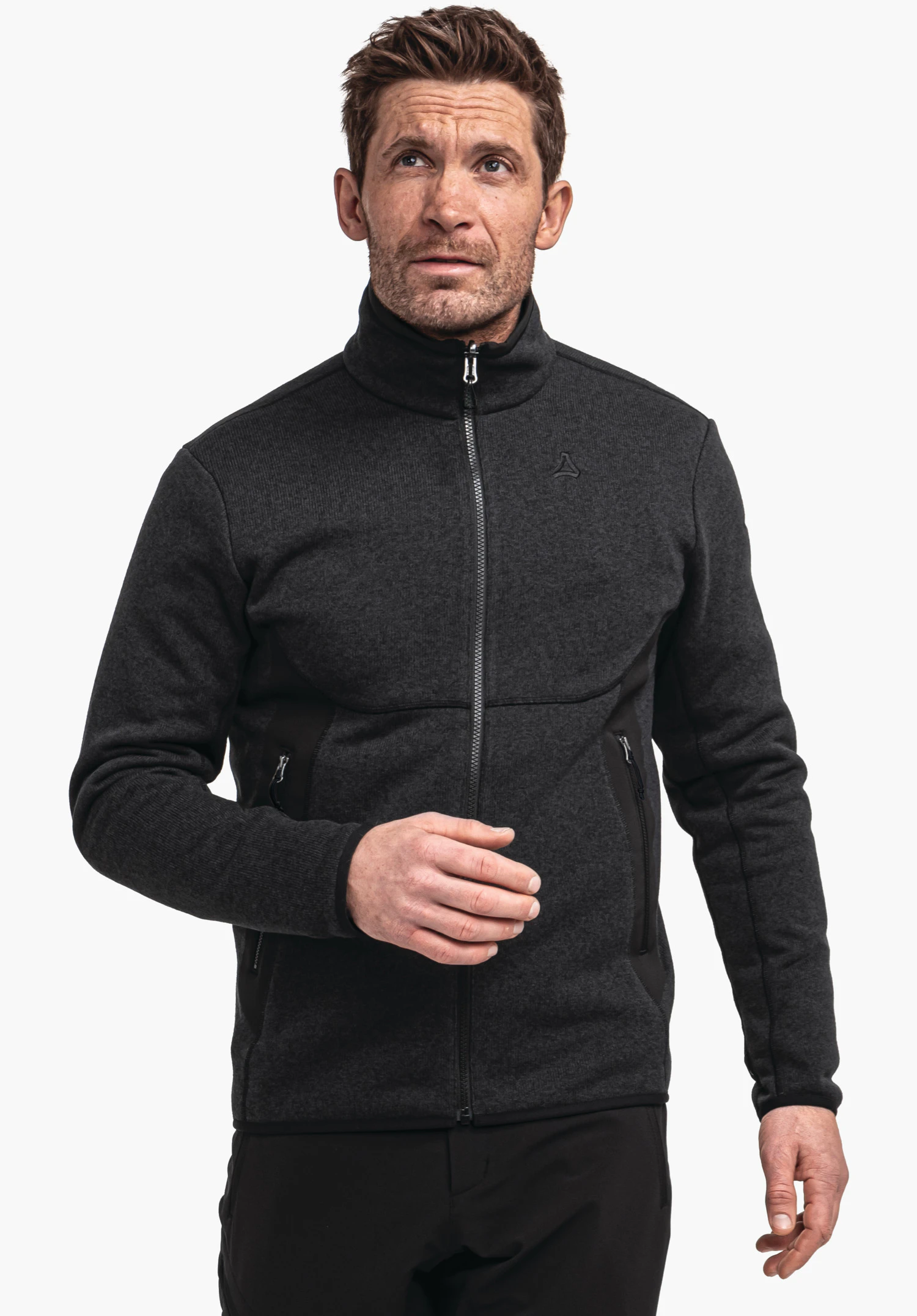 CIRC Fleece Jk Style Yew MNS Mann trägt eine dunkelschwarze Fleecejacke, schließt den Reißverschluss; Blick nach oben. Schöffel-Logo auf der Brust. Weißer Hintergrund, stehende Aufnahme bis zur Hüfte.
