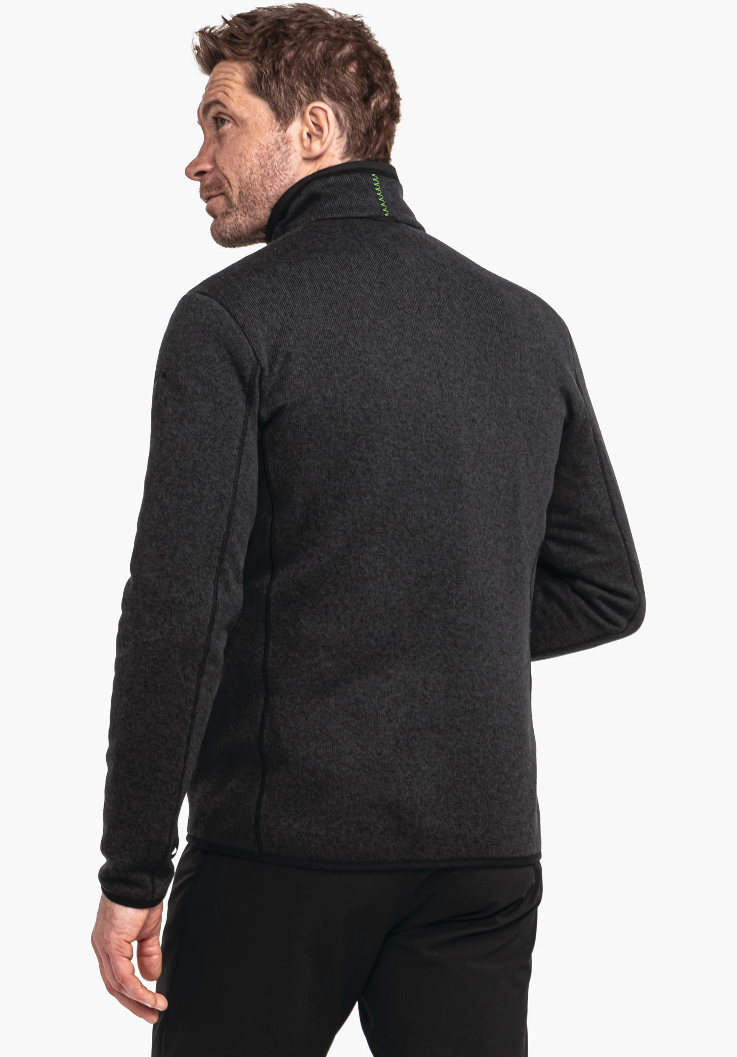 CIRC Fleece Jk Style Yew MNS deep black fleece jacket worn by a man looking over his shoulder; green decorative stitching at the collar; light studio background.