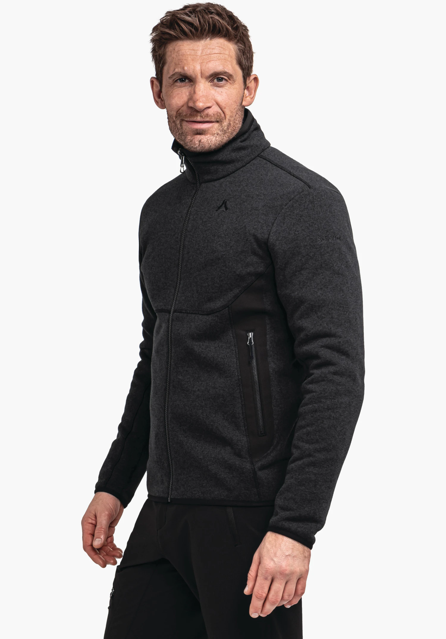 CIRC Fleece Jk Style Yew MNS dark grey jacket with Schöffel logo, worn by a standing man with a slight smile; visible zip and side pockets, black trousers in front of a light background. Text: "Schöffel".