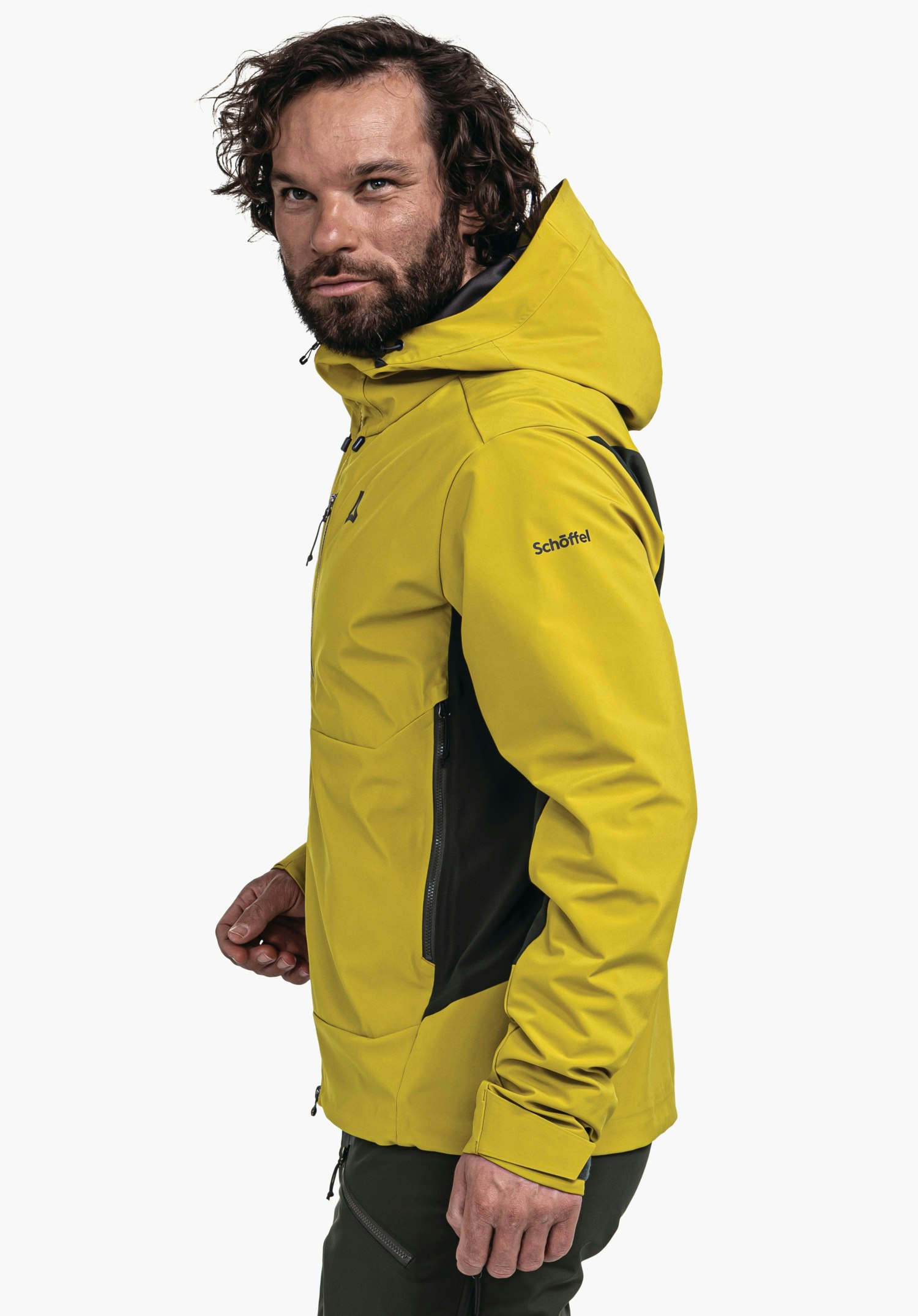 Softshell Jk Style Milagle MNS Mann trägt hellgelbe Jacke mit Schöffel-Logo an der Brust; steht halbseitlich, schaut zur Seite; dunkelgrüne Einsätze, weißer Hintergrund. Text auf Ärmel: "Schöffel".