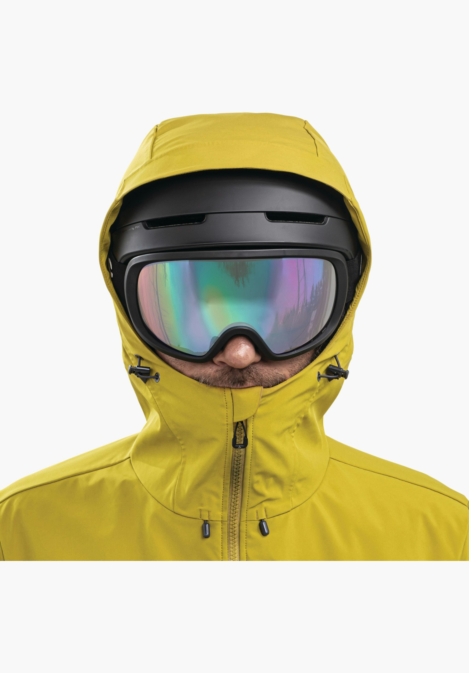 Softshell Jk Style Milagle MNS, die gelbe, helmkompatible Kapuze über einem schwarzen Skihelm sowie der hohe Kragen mit Frontreißverschluss und Kordelzug, Nahaufnahme vor weißem Hintergrund.
