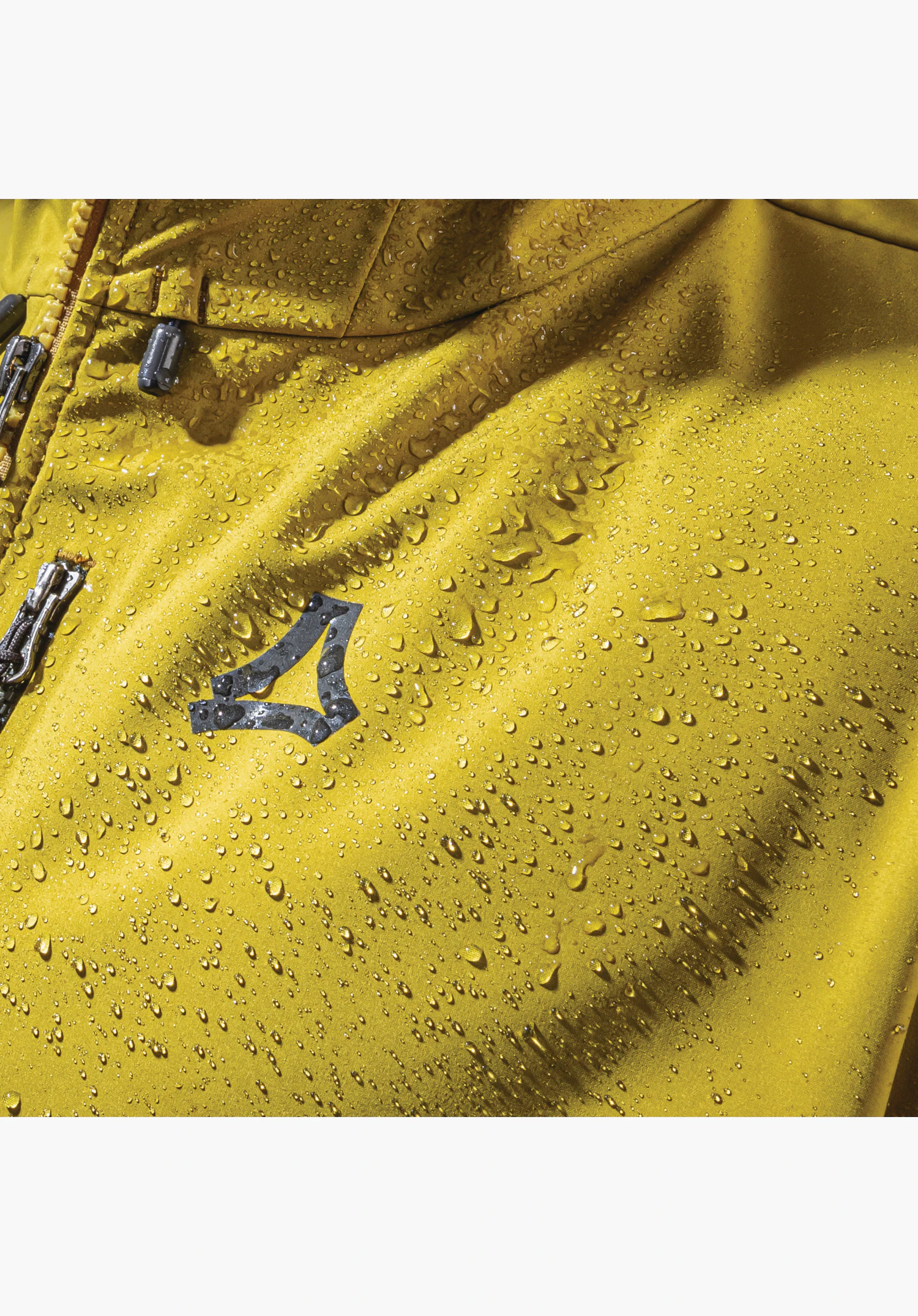 Softshell Jk Style Milagle MNS toont de waterafstotende eigenschap van het gele materiaal met parelende waterdruppels en het Schöffel-logo. Close-up voor een witte/neutrale achtergrond.