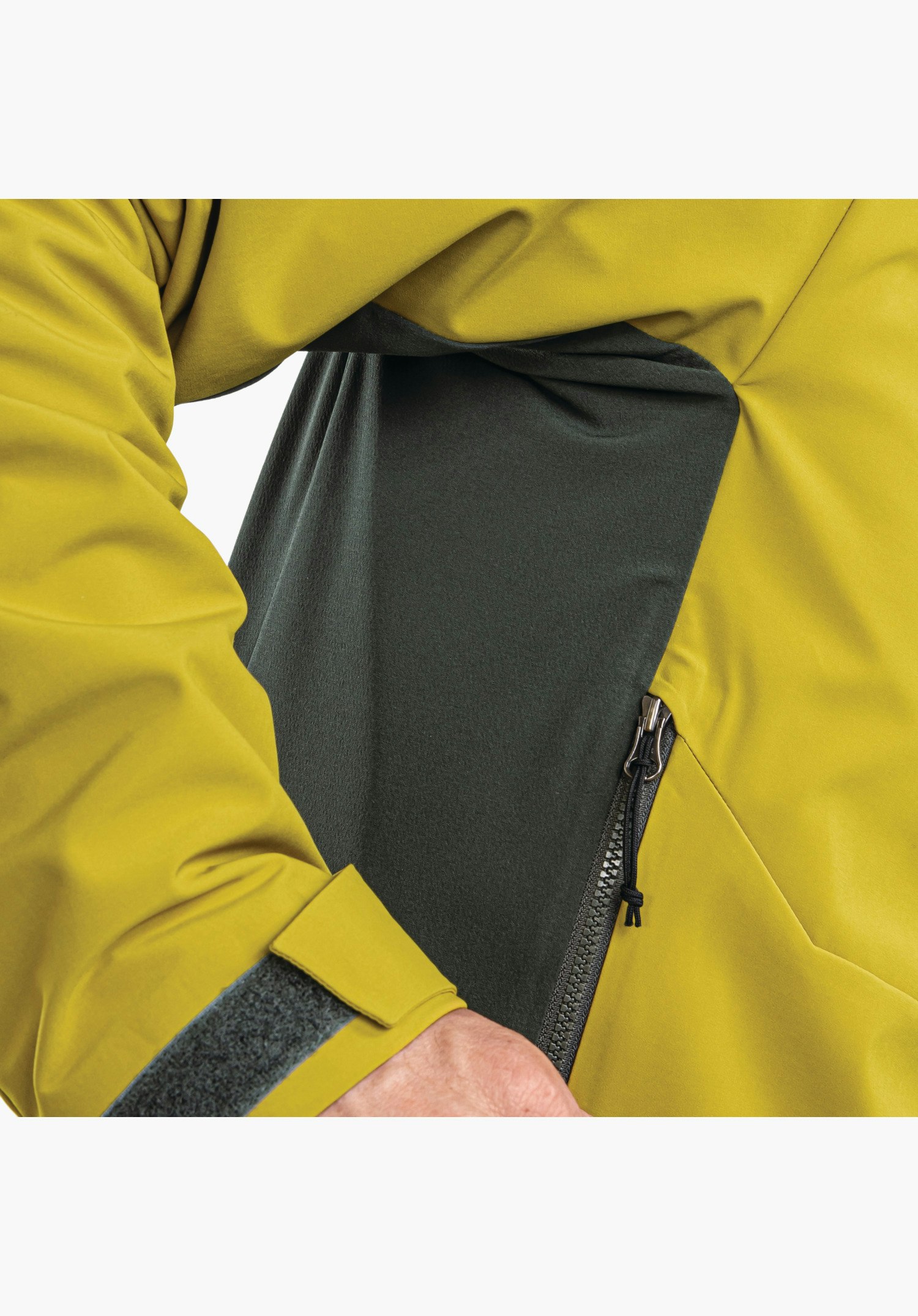 Softshell Jk Style Milagle MNS, Fokus auf den seitlichen Reißverschluss, den verstellbaren Ärmelabschluss mit Klettverschluss und das dunkle Kontrastpanel im gelben Softshell-Material, Nahaufnahme vor weißem/neutralem Hintergrund.