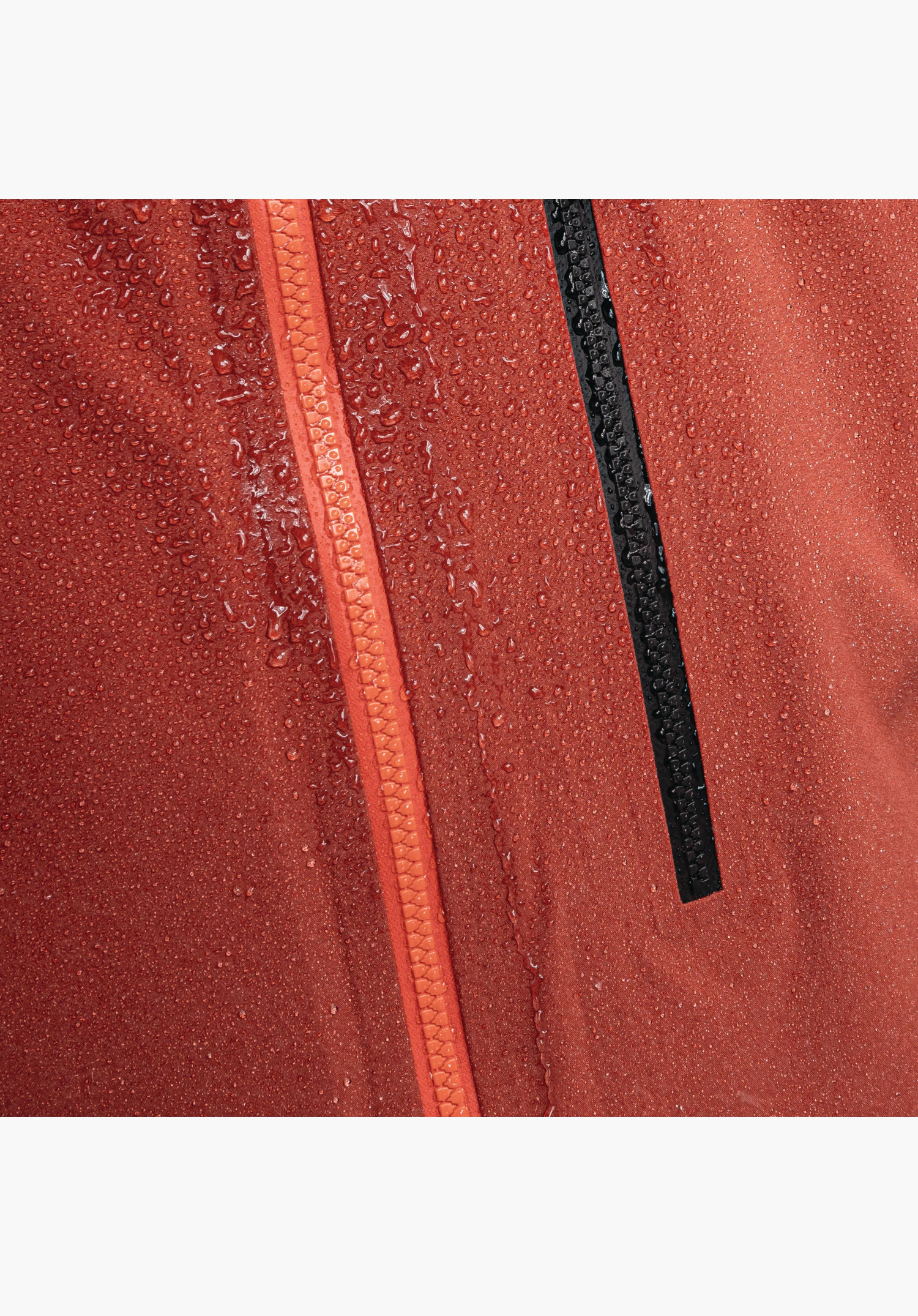 Jacket Style Milagle MNS zeigt das rote, wasserabweisende Material mit abperlenden Wassertropfen sowie einen orangefarbenen Reißverschluss und einen schwarzen Akzent als Nahaufnahme vor weißem Hintergrund.