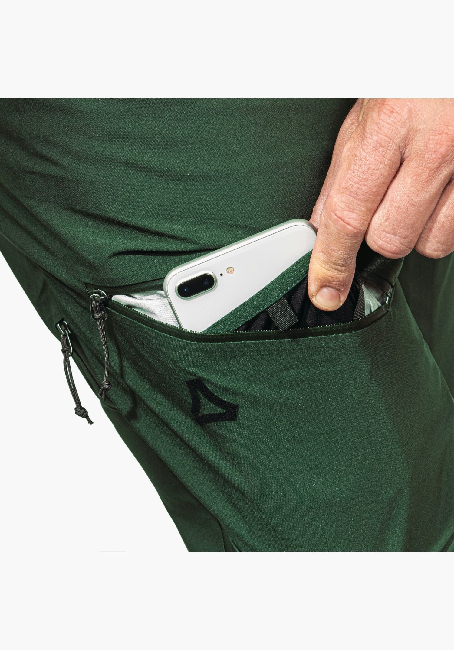 Pants Style Milagle MNS features the green thigh pocket with zip and integrated Smart Device Pocket securely holding a smartphone, accentuated by the black Schöffel logo. Close-up against a white background.