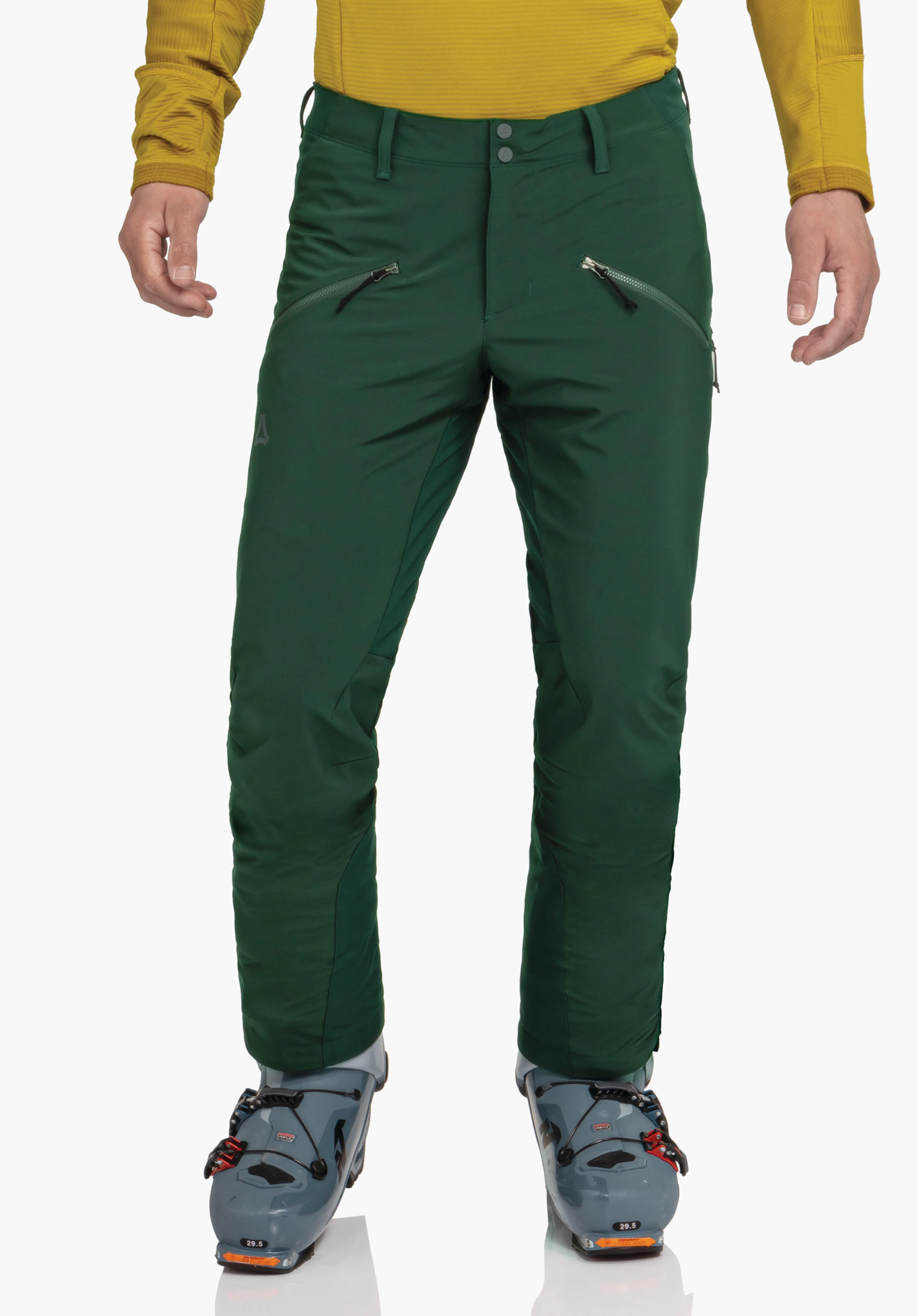 Softshell Pt Style Milagle MNS pantalon vert foncé, porté par une personne debout; poches zippées diagonales, logo Schöffel sur la cuisse gauche; haut jaune, chaussures de ski bleu clair avec «29.5».