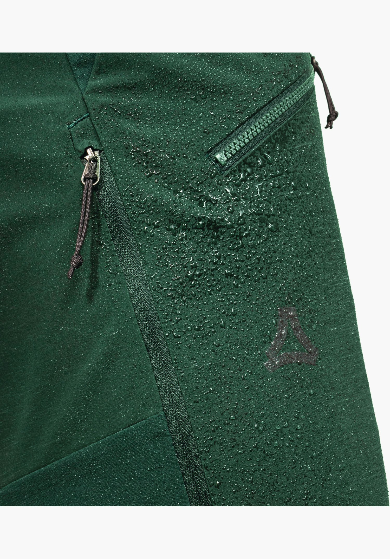 Softshell Pt Style Milagle MNS, vue détaillée du tissu vert avec des gouttes d'eau qui perlent, des fermetures éclair avec tirettes et le logo Schöffel, gros plan sur fond blanc.