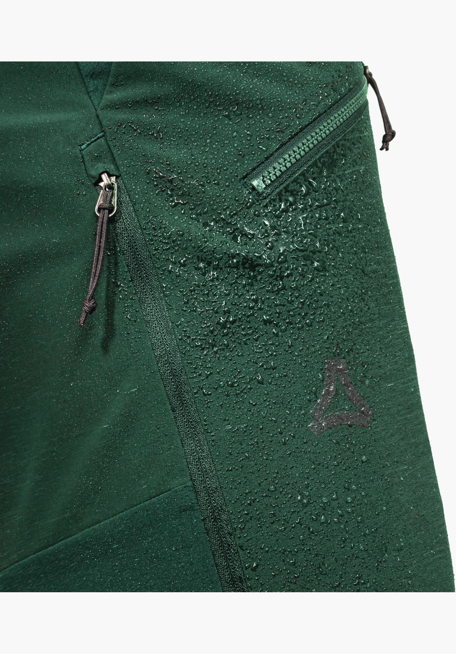 Softshell Pt Style Milagle MNS, detail of the green fabric with water droplets beading off, zips with pull tabs and the Schöffel logo, close-up against a white background.