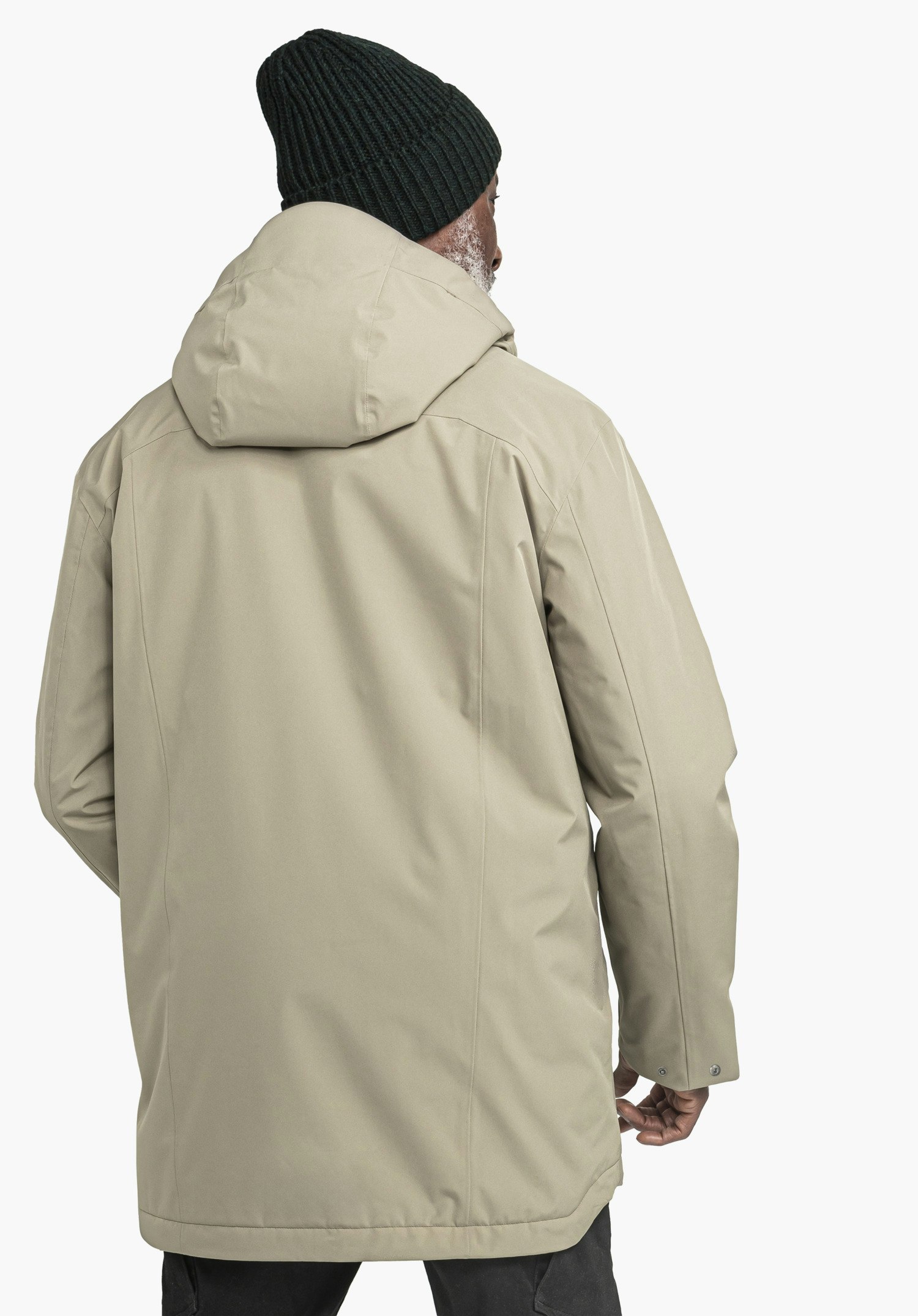 Ins Parka Style Malkay MNS hellbrauner Parka, Person trägt ihn, Rückenansicht; Kapuze aufliegend, dunkelgrüne Strickmütze, sichtbarer weißer Bart, stehende Pose vor weißem Hintergrund.