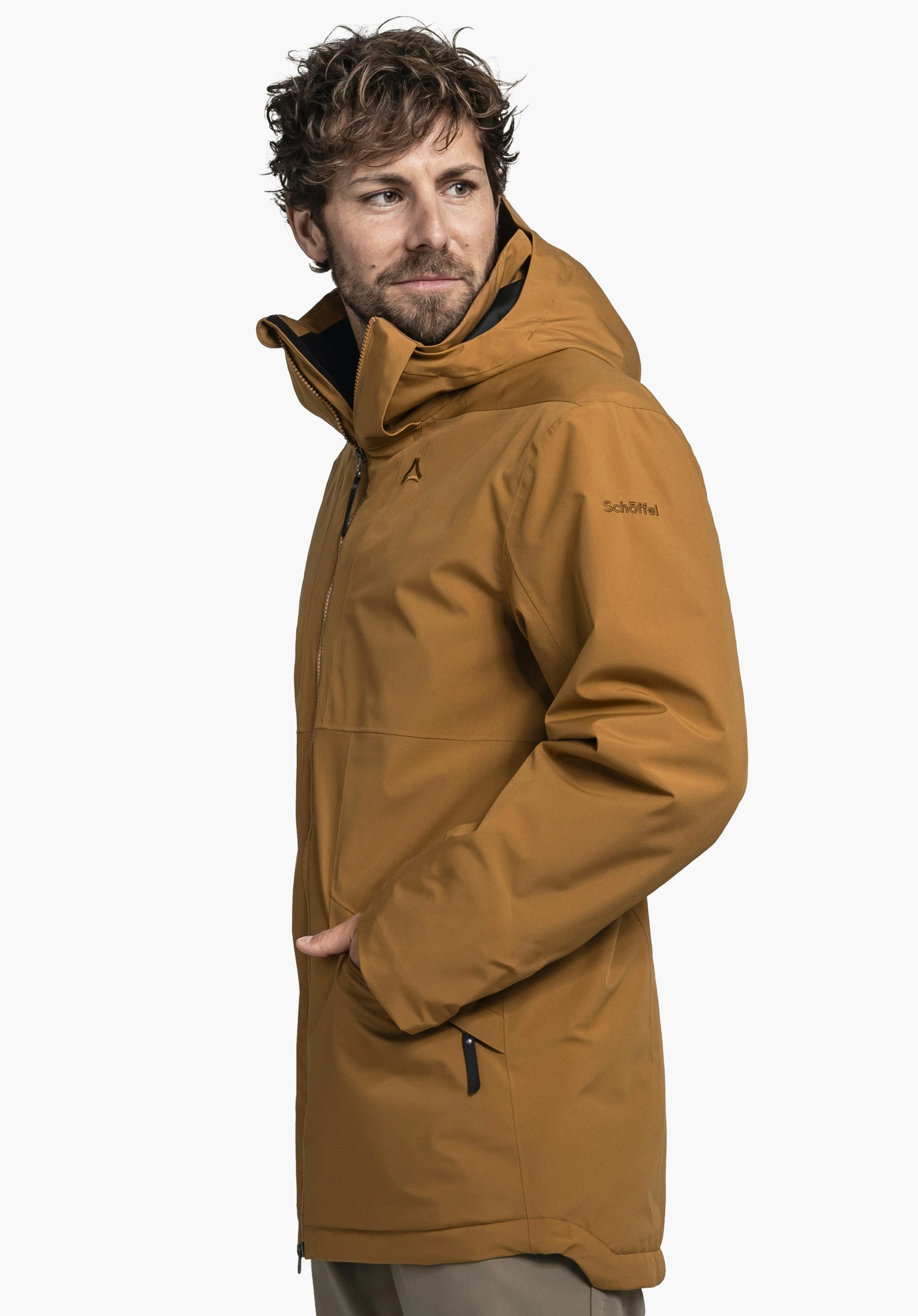 Ins Parka Style Malkay MNS dunkel orange Parka (Schöffel-Logo) wird von einem Mann getragen, er schaut nach rechts, Hände in Tasche, neutraler weißer Hintergrund. Text auf Ärmel: "Schöffel".