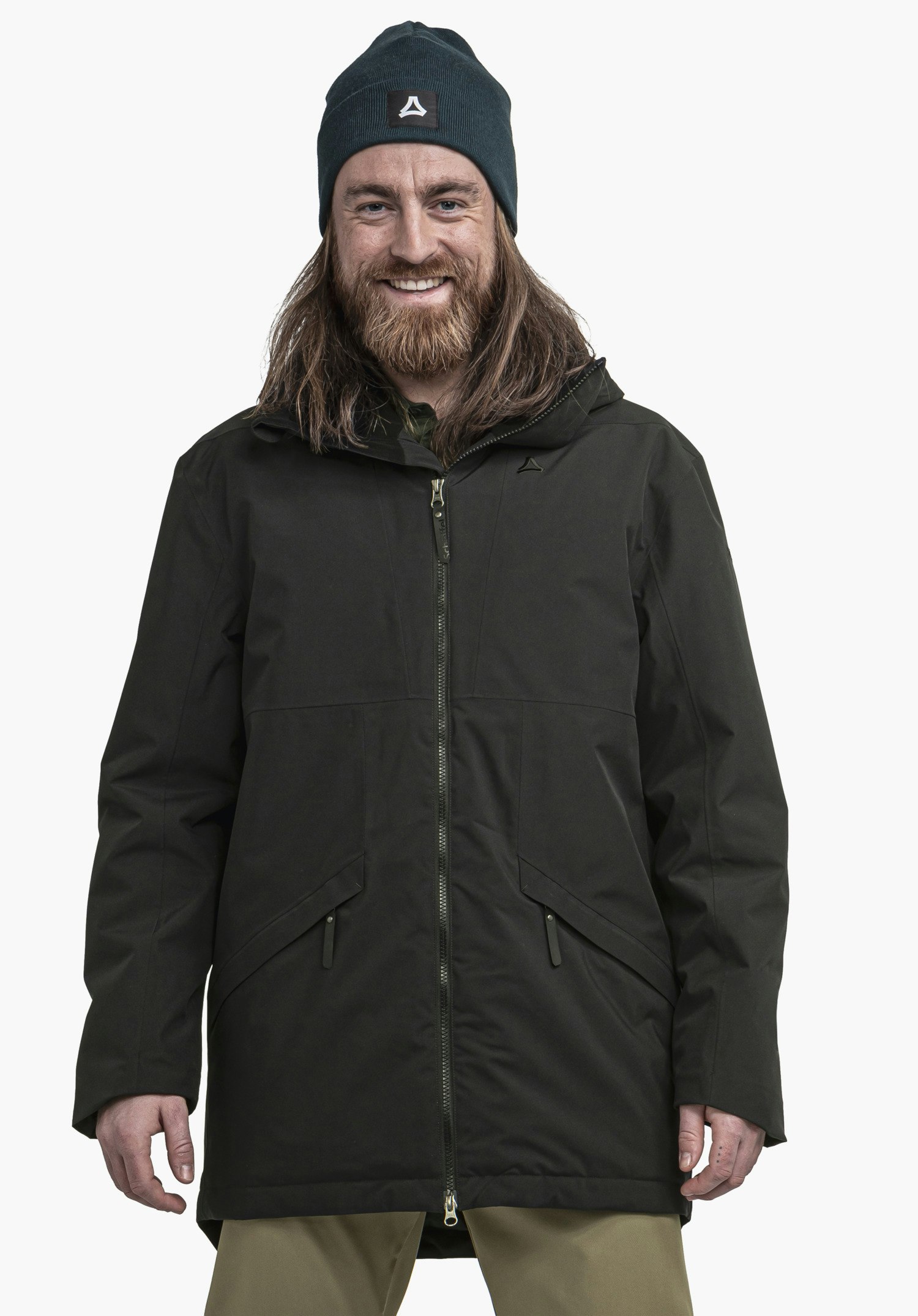 Ins Parka Style Malkay MNS Mann mit Bart trägt schwarze Jacke und dunkelgrüne Mütze mit Schöffel-Logo, lächelt und steht frontal vor weißem Hintergrund.
