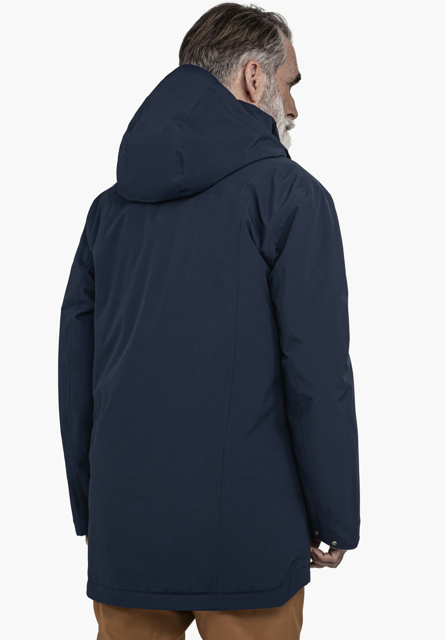 Ins Parka Style Malkay MNS dunkelblaue Jacke, getragen von einer Person, die steht und den Kopf leicht nach rechts dreht; Kapuze aufgesetzt; Kontext: neutraler weißer Hintergrund, braune Hose sichtbar.