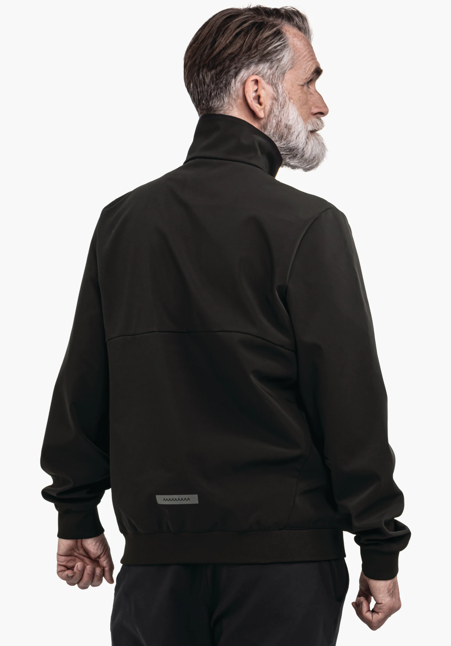 Softshell Jk Style Suavio MNS veste vert foncé, portée par un homme âgé tournant la tête sur le côté; vue de dos devant un fond blanc lumineux.