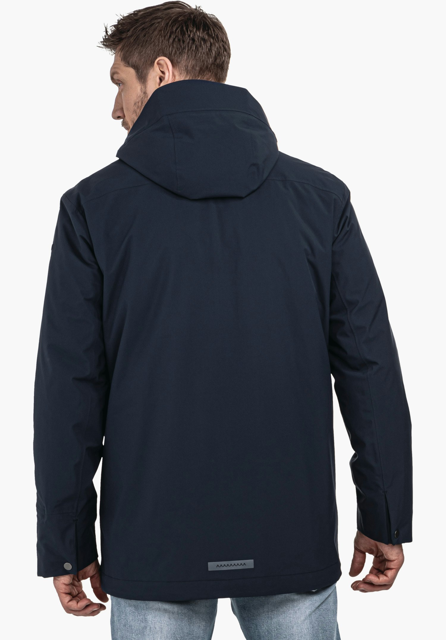 3in1 Parka Style Borkol MNS donkerblauwe jas met capuchon; persoon draagt deze met de rug naar de camera en kijkt naar rechts; ontspannen staande houding voor een neutrale lichtgrijze achtergrond.