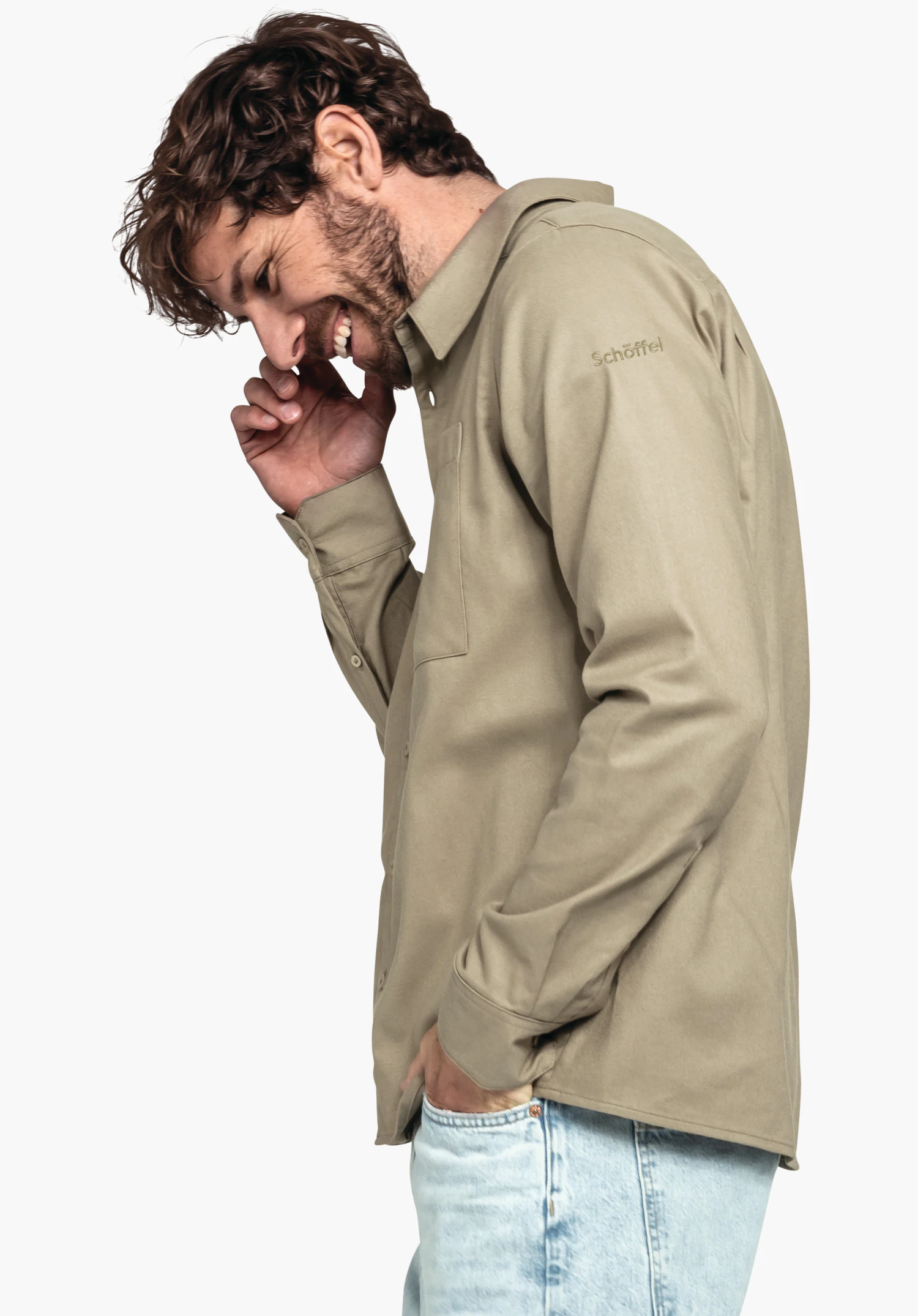 Shirt Style Kleion MNS Mann in hellbraunem Hemd lächelt, hält Hand ans Gesicht; andere Hand in hellblauer Jeans-Tasche; weißer Hintergrund. Text auf Ärmel: "Schöffel".