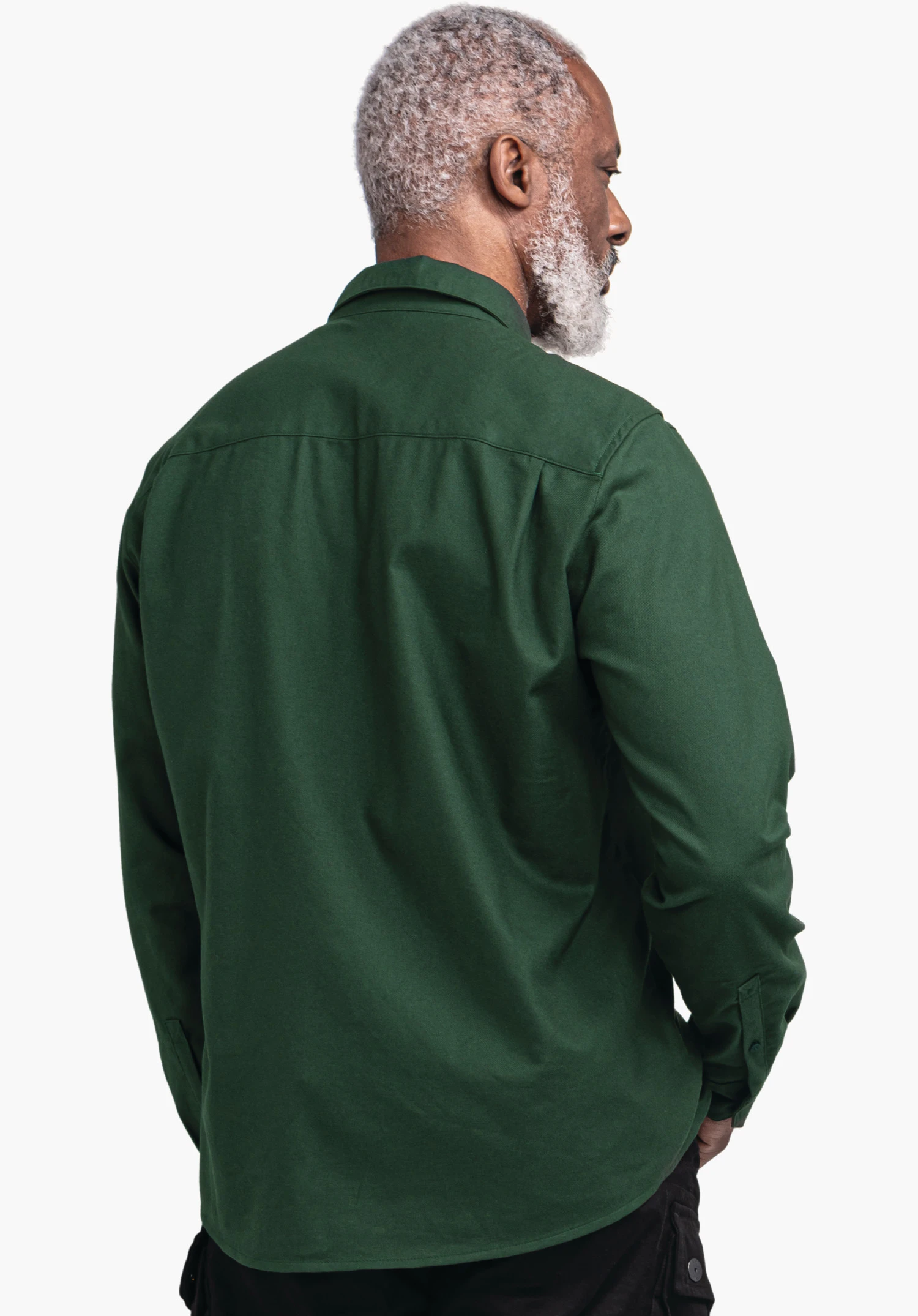 Shirt Style Kleion MNS Hemd in grün dunkel, getragen von einer Person, steht mit dem Rücken zur Kamera und blickt seitlich weg; kurze weiße Haare und Bart; neutraler weißer Hintergrund.