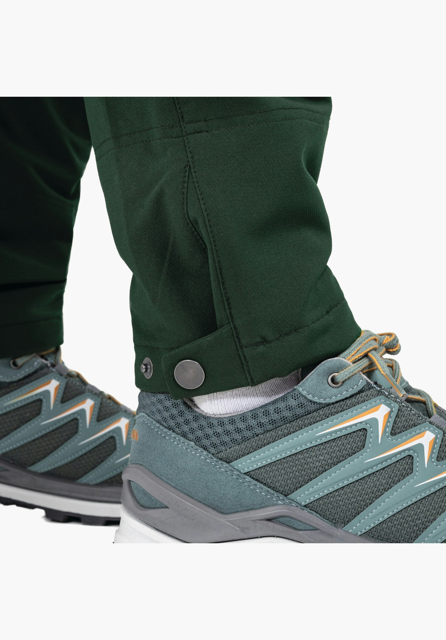Pants Style Cascata WMS, de verstelbare broekspijpzoom met metalen drukknoop op de groene broekspijp. Close-up tegen een witte achtergrond.