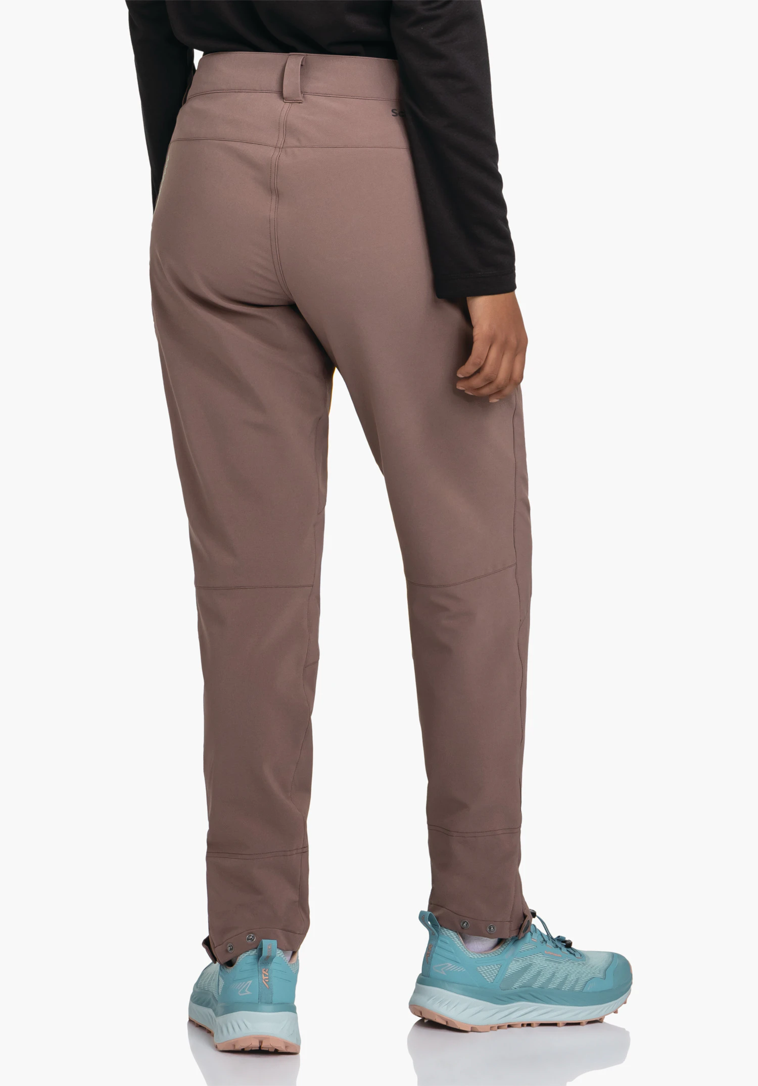 Pants Style Cascata WMS pantalon violet foncé, porté de dos; personne debout, main droite détendue sur le côté; haut noir, chaussures bleu clair; fond studio blanc.