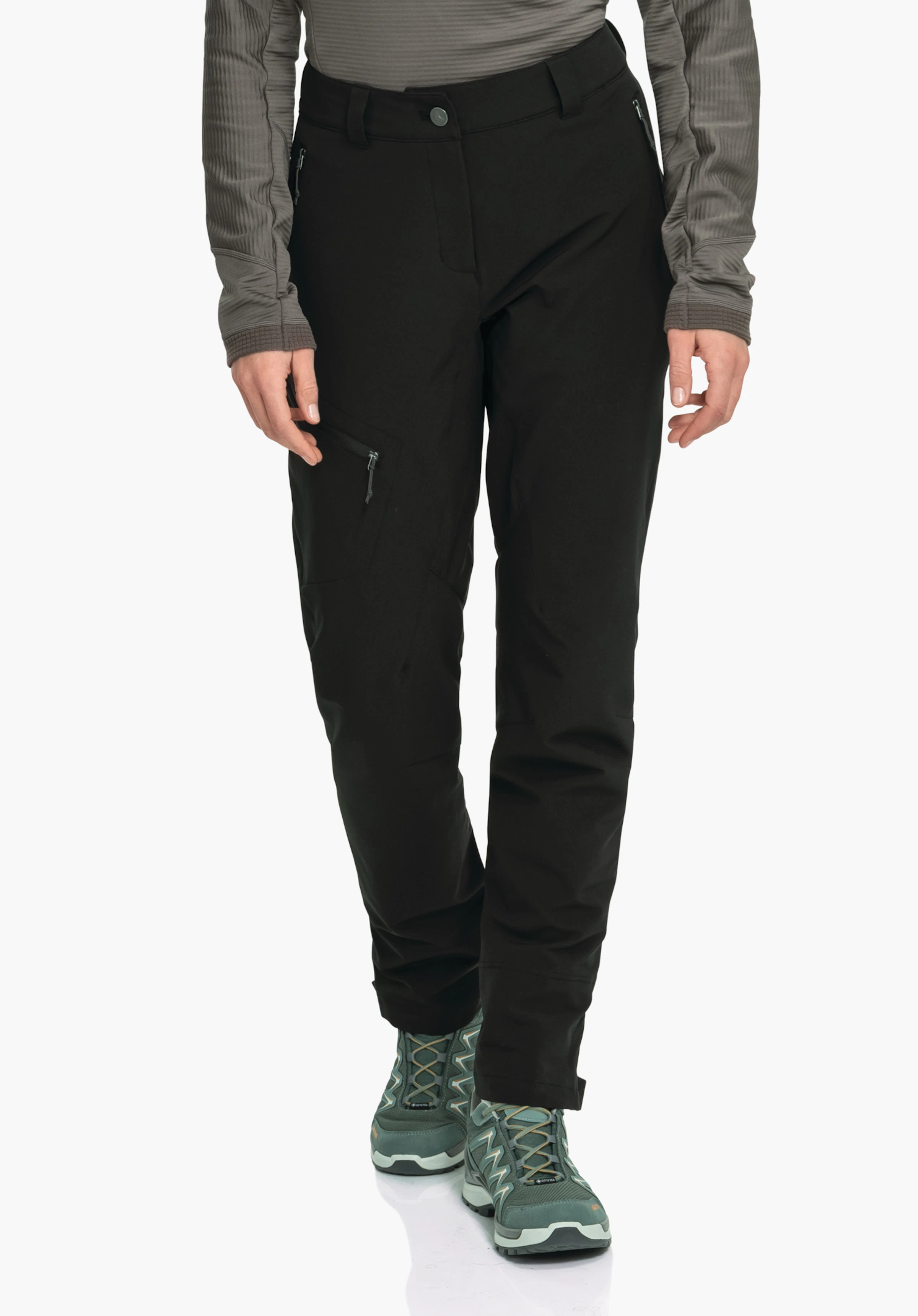Pants Style Cascata WMS Schwarze Wanderhose, an Person getragen, leicht vorwärts schreitend; rechte Oberschenkeltasche mit Reißverschluss sichtbar; Hände locker seitlich; Kontext: neutraler heller Hintergrund, dunkelgrüne Wanderschuhe.