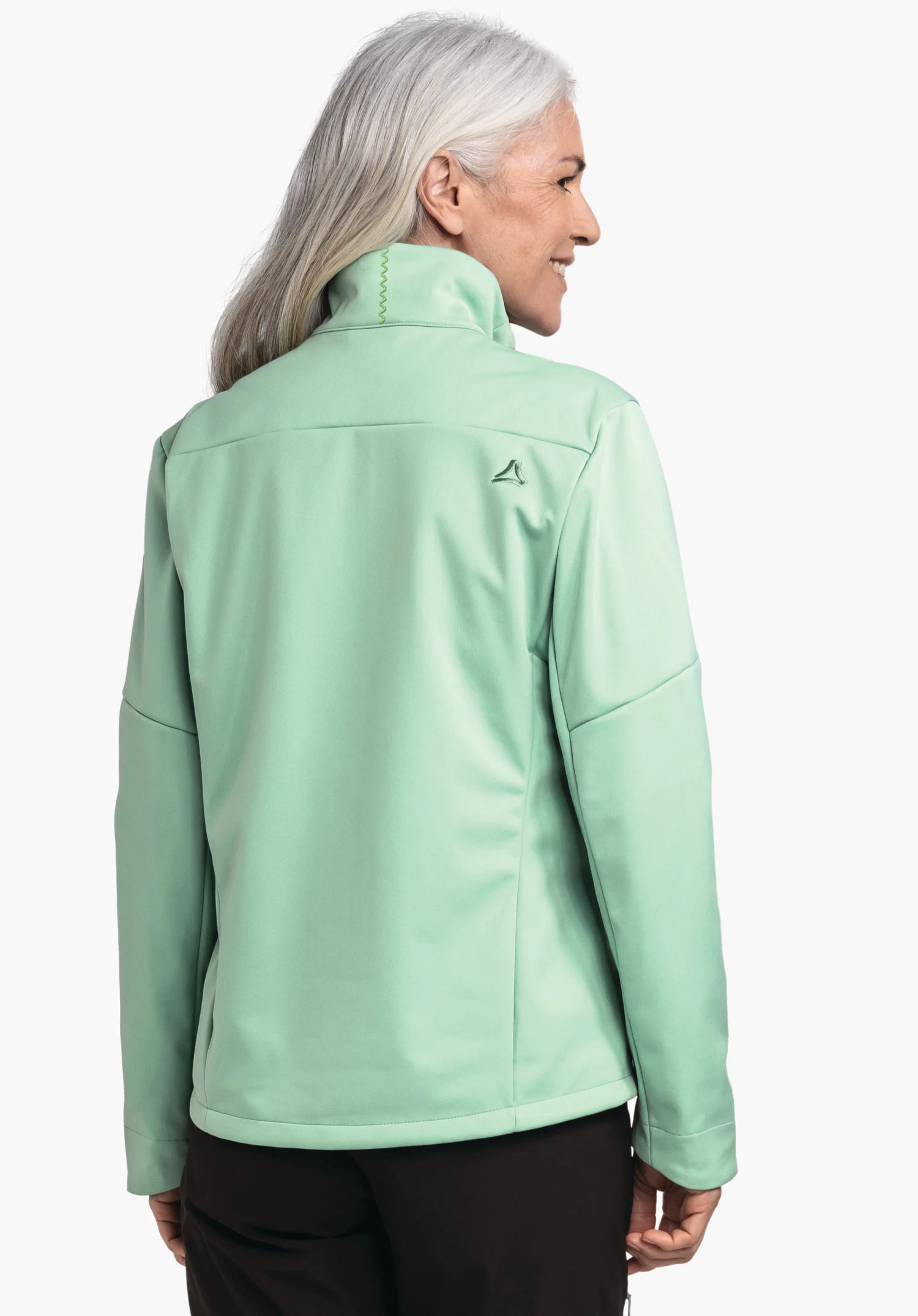 Softshell Jk Style Fracon WMS lichtgroene jas, gedragen door een vrouw met wit haar die zijwaarts glimlacht; Schöffel-logo in donkergroen op de rug; witte studioachtergrond.
