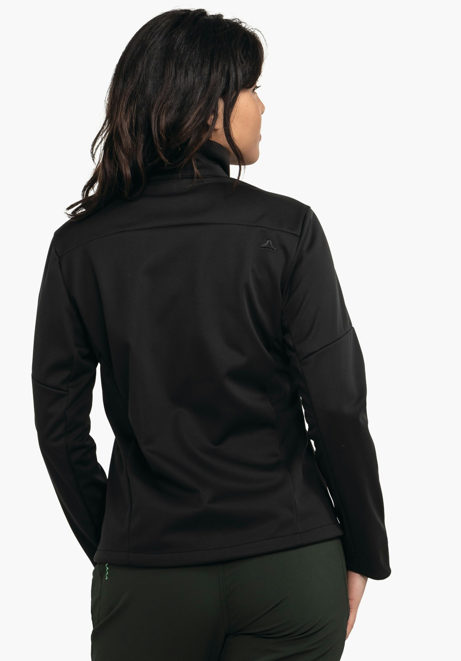 Softshell Jk Style Fracon WMS Schwarze Jacke mit Schöffel-Logo auf rechter Schulter, von einer Person von hinten getragen; Person blickt seitlich, weißer Hintergrund, dunkelgrüne Hose sichtbar.