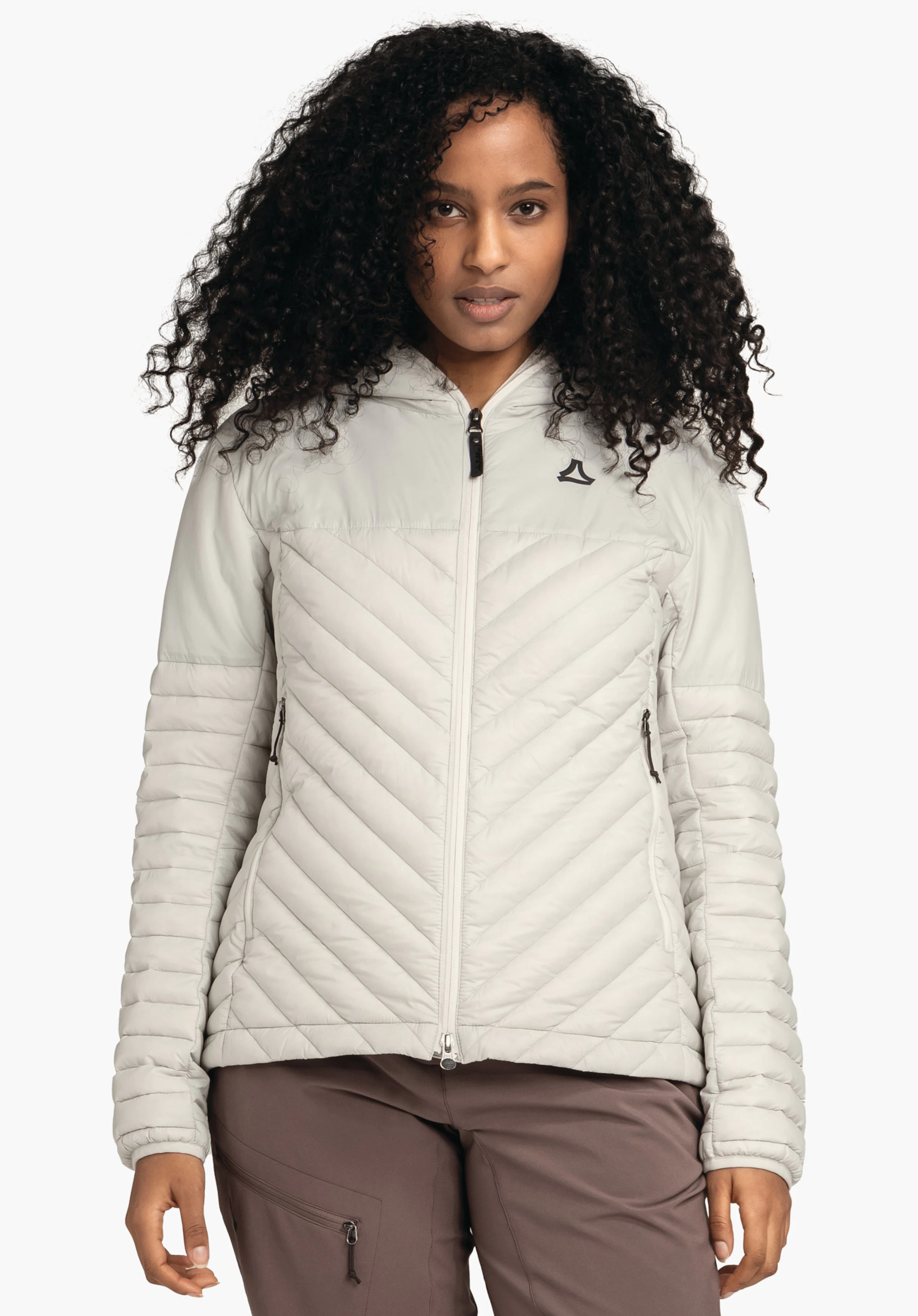 Down Jacket Style Cascata WMS hellgraue Steppjacke mit Reißverschluss und Schöffel-Logo, frontal getragen; Person steht ruhig, Gesicht sichtbar; gestepptes Muster, seitliche Reißverschlusstaschen, heller weißer Studiohintergrund.