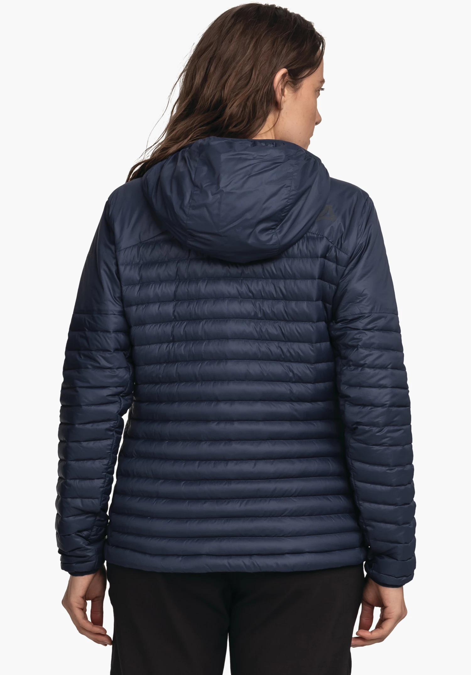 Down Jacket Style Cascata WMS donkerblauwe gewatteerde jas met capuchon, gedragen door een persoon met de rug naar de camera; armen ontspannen langs het lichaam; eenvoudige witte achtergrond, zwarte broek; Schöffel-logo zichtbaar.