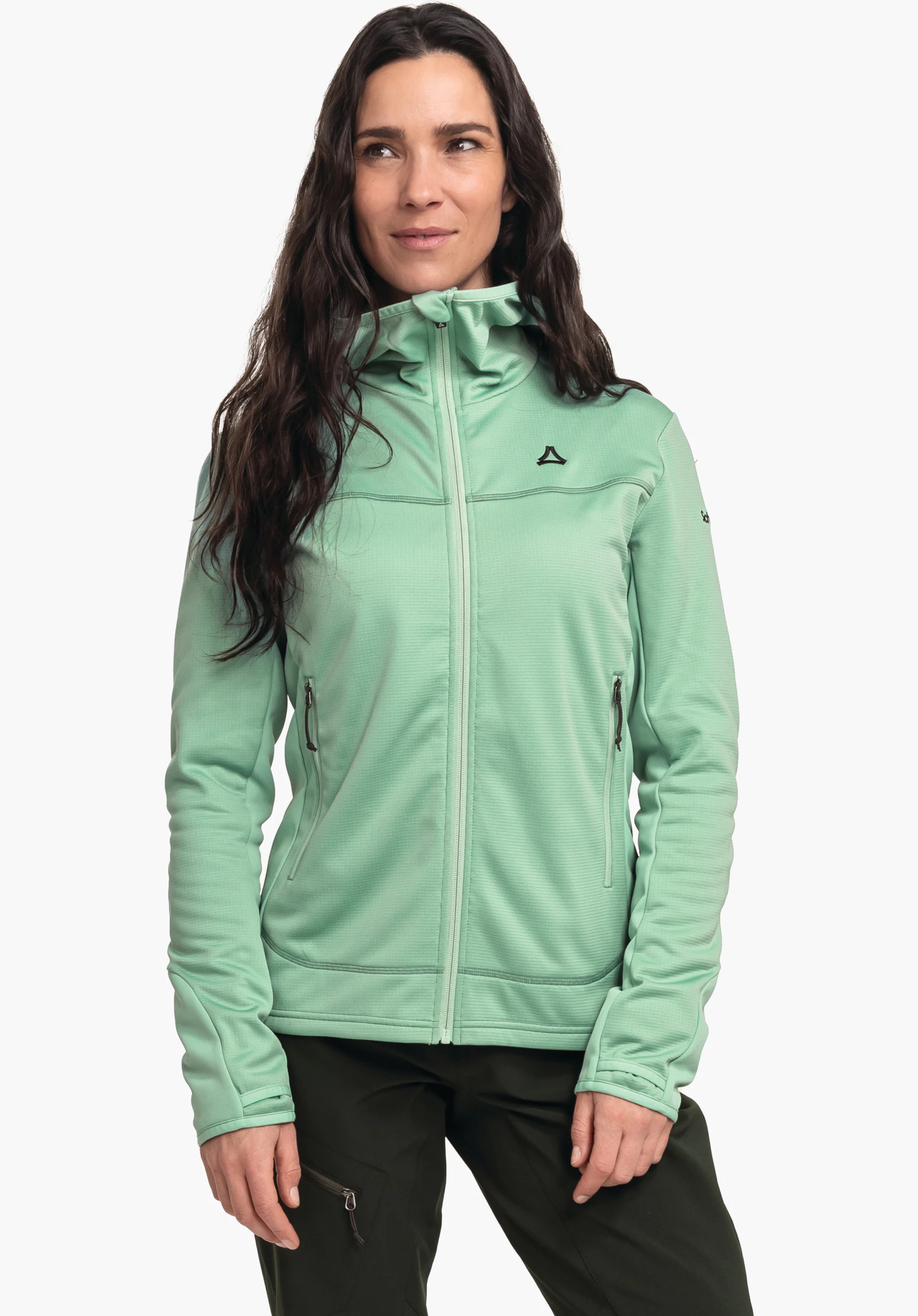 Fleece Hoody Style Milagle WMS Femme portant une veste vert clair, debout calmement et regardant de côté; logo Schöffel sur la poitrine, capuche relevée; fond blanc neutre, pantalon vert foncé.