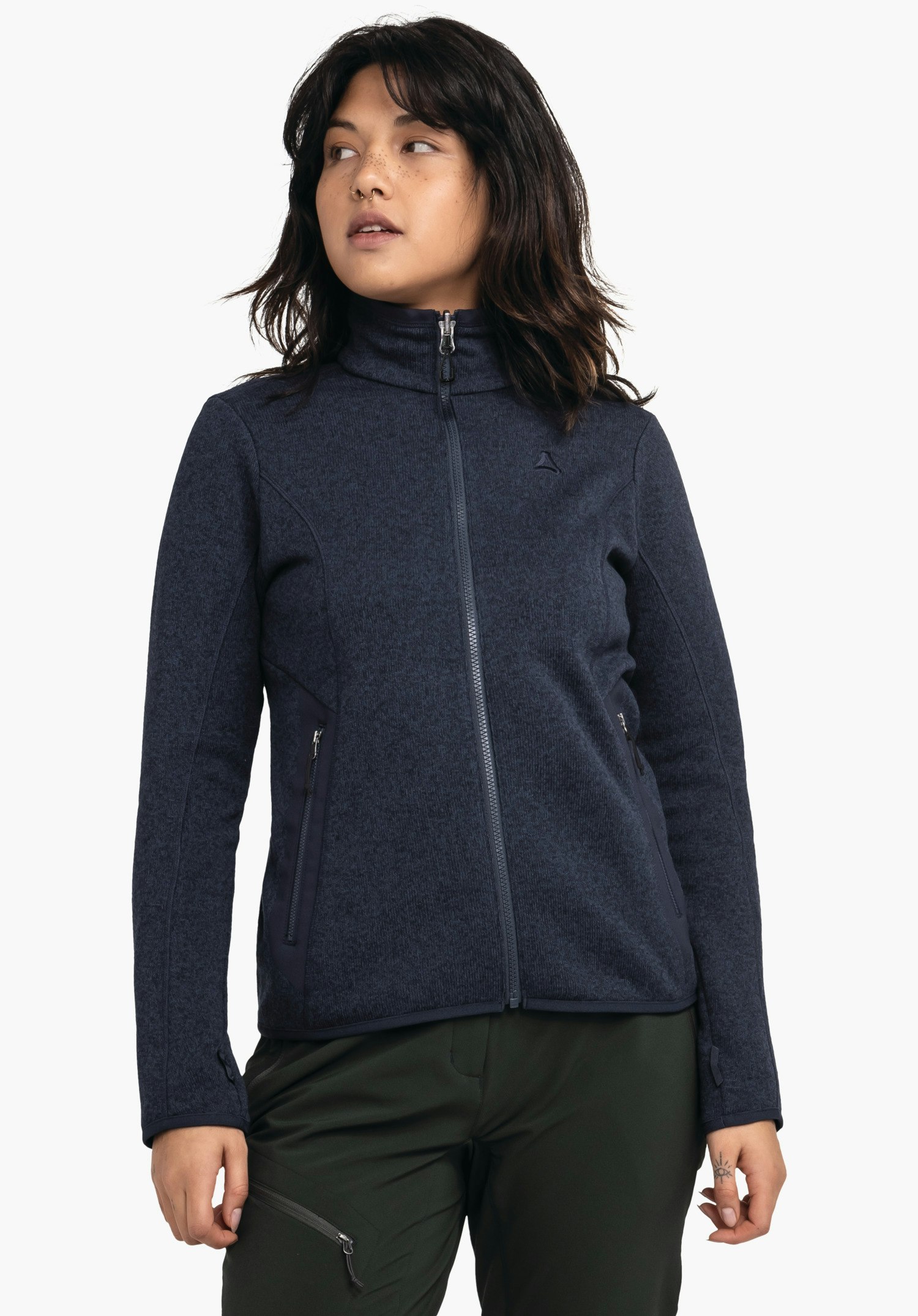 CIRC Fleece Jk Style Yew WMS Veste ajustée bleu foncé avec zip fermé et logo Schöffel, portée par une personne debout devant un fond blanc; pantalon vert foncé visible, bras détendus le long du corps.