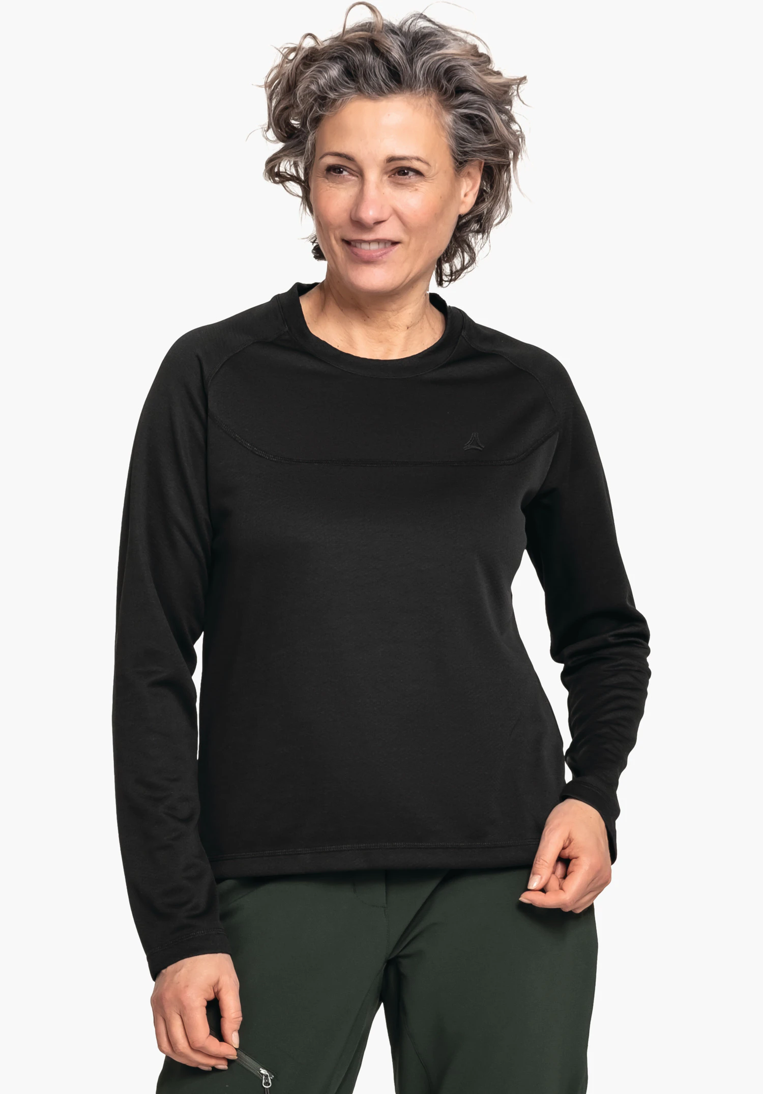 CIRC Longsleeve Smue WMS black long-sleeve top worn by a smiling woman looking slightly sideways; Schöffel logo on the chest; standing against a neutral background, dark green trousers visible.