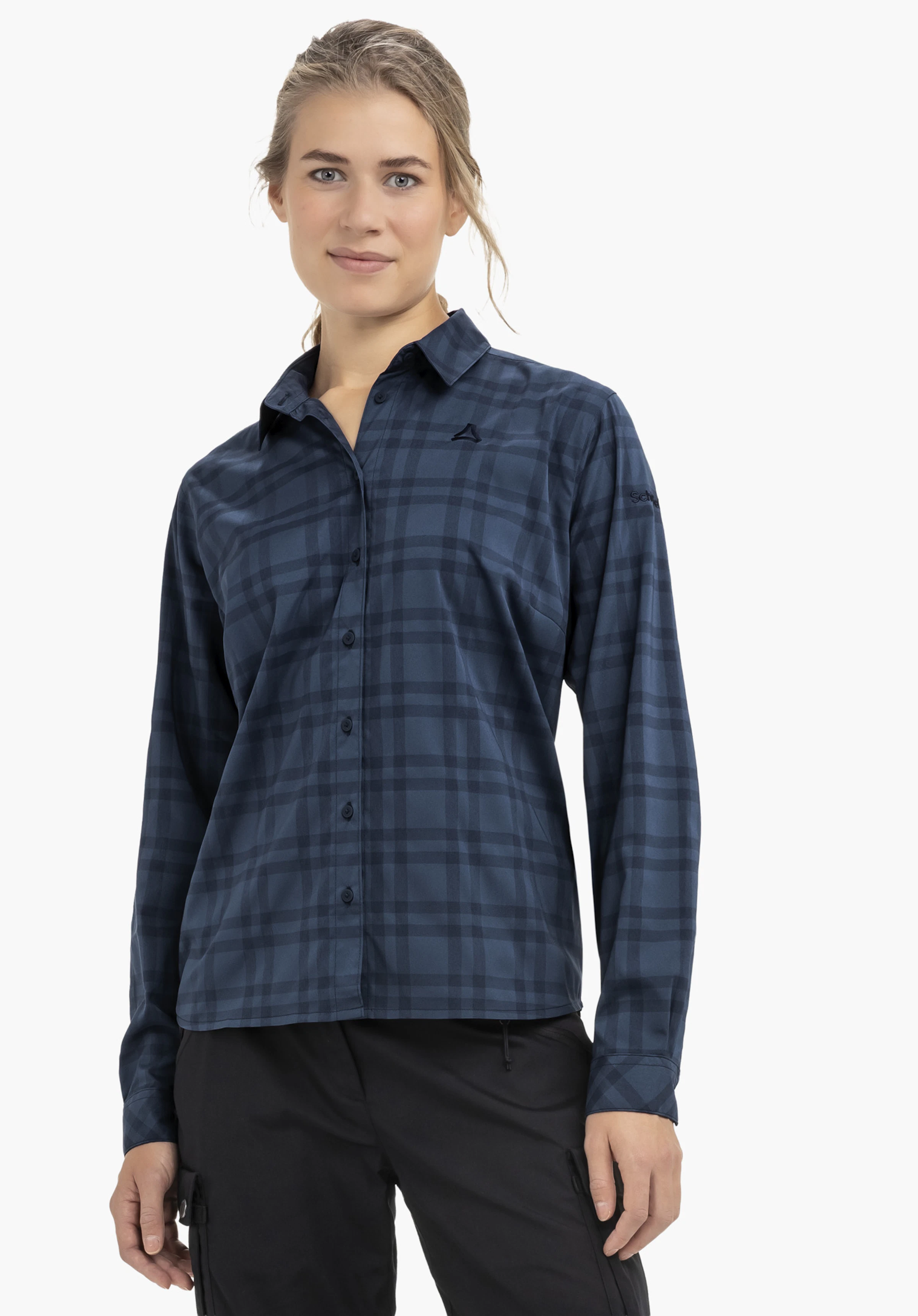 Blouse Style Yekuro WMS Dunkelblaue kariertes Langarmhemd mit Schöffel-Logo, getragen von Frau, frontal stehend mit seitlich hängenden Händen, schwarze Hose, neutraler weißer Studiohintergrund.