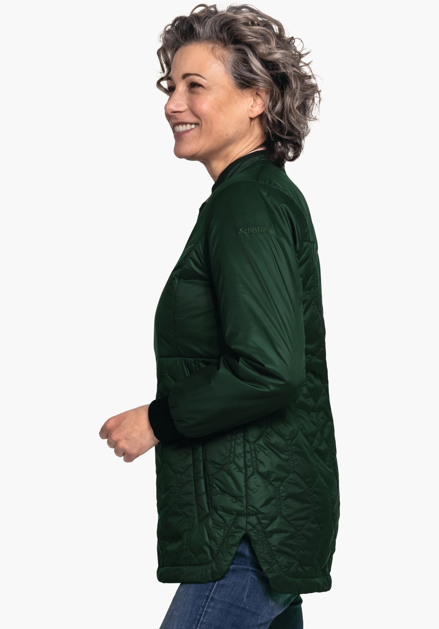 Ins Jacket Style Malkay WMS veste matelassée vert foncé; femme souriante en profil la porte sur un jean bleu devant fond clair. Inscription "Schöffel" sur le haut du bras gauche.