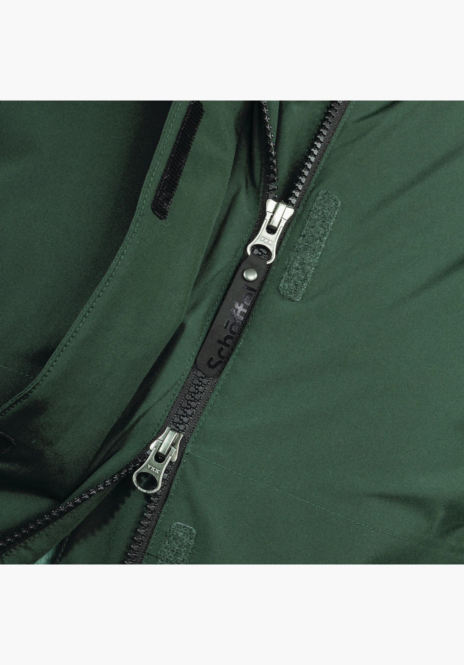 Ins Parka Style Malkay WMS toont de zwarte tweewegrits met een trekker met het Schöffel-logo en klittenband op het groene materiaal als close-up voor een witte achtergrond.