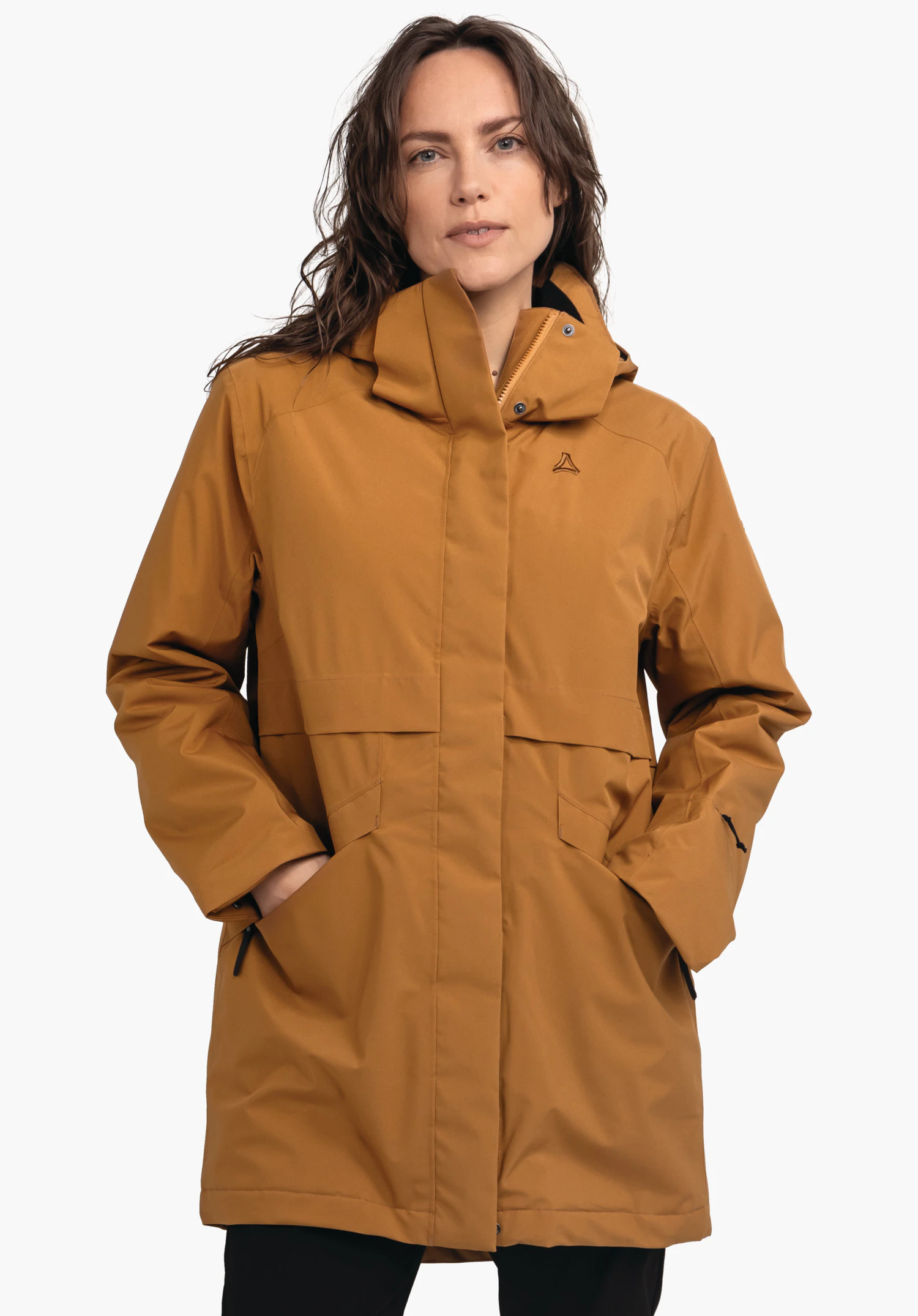 Ins Parka Style Malkay WMS donkeroranje parka met Schöffel-logo; gedragen door een vrouw, handen in de zakken, capuchon los opgezet; witte achtergrond.