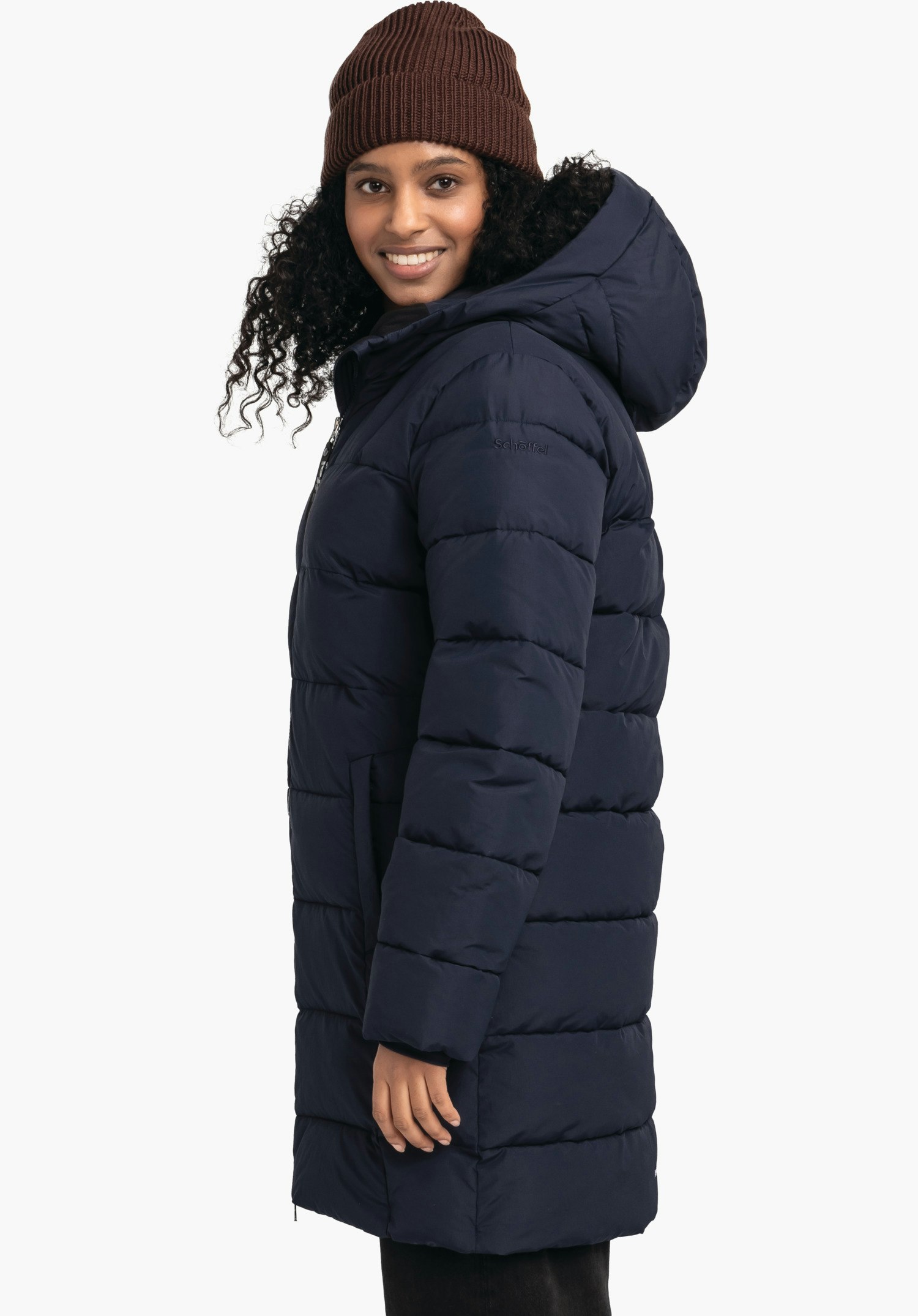 Ins Parka Style Boslix WMS dark blue quilted parka with hood, worn side-on by a smiling woman; she wears a dark brown beanie, white background. Sleeve text: "Schöffel".